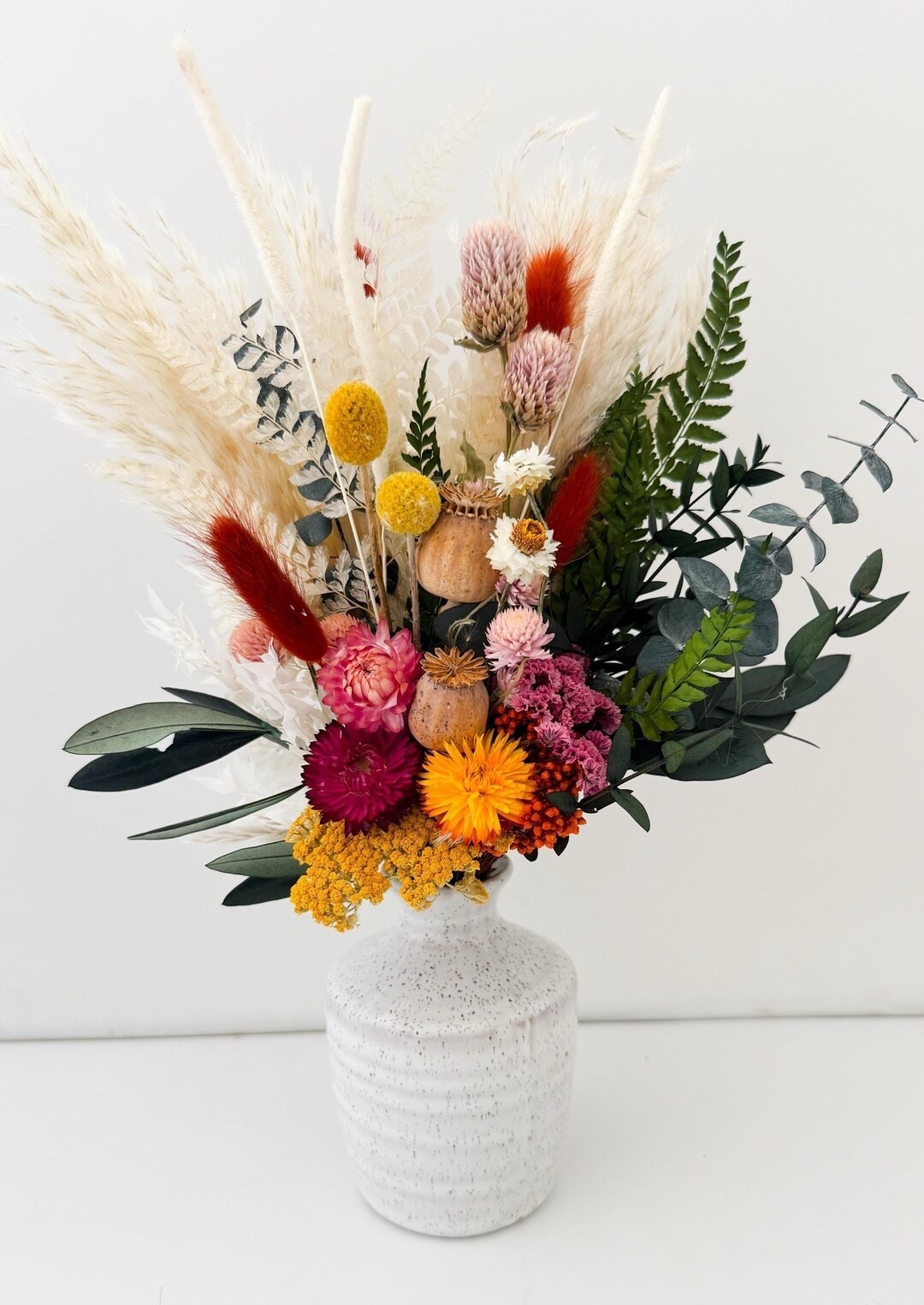 Bring effortless, natural texture into your space with this everlasting dried arrangement featuring pampas grass, eucalyptus, olive, bunny tails, yarrow, and more. Designed as a mini centerpiece, it’s the perfect low-maintenance accent for weddings, gifting, or everyday home decor—no watering needed, just timeless beauty. Available with or without a petite bud vase for a complete, styled look. 🌾✨ #LTKHome #DriedFlowers #HomeDecor #BohoStyle #WeddingDecor #NeutralAesthetic #SustainableStyle #LTKFinds

#LTKHome #LTKWedding #LTKSeasonal