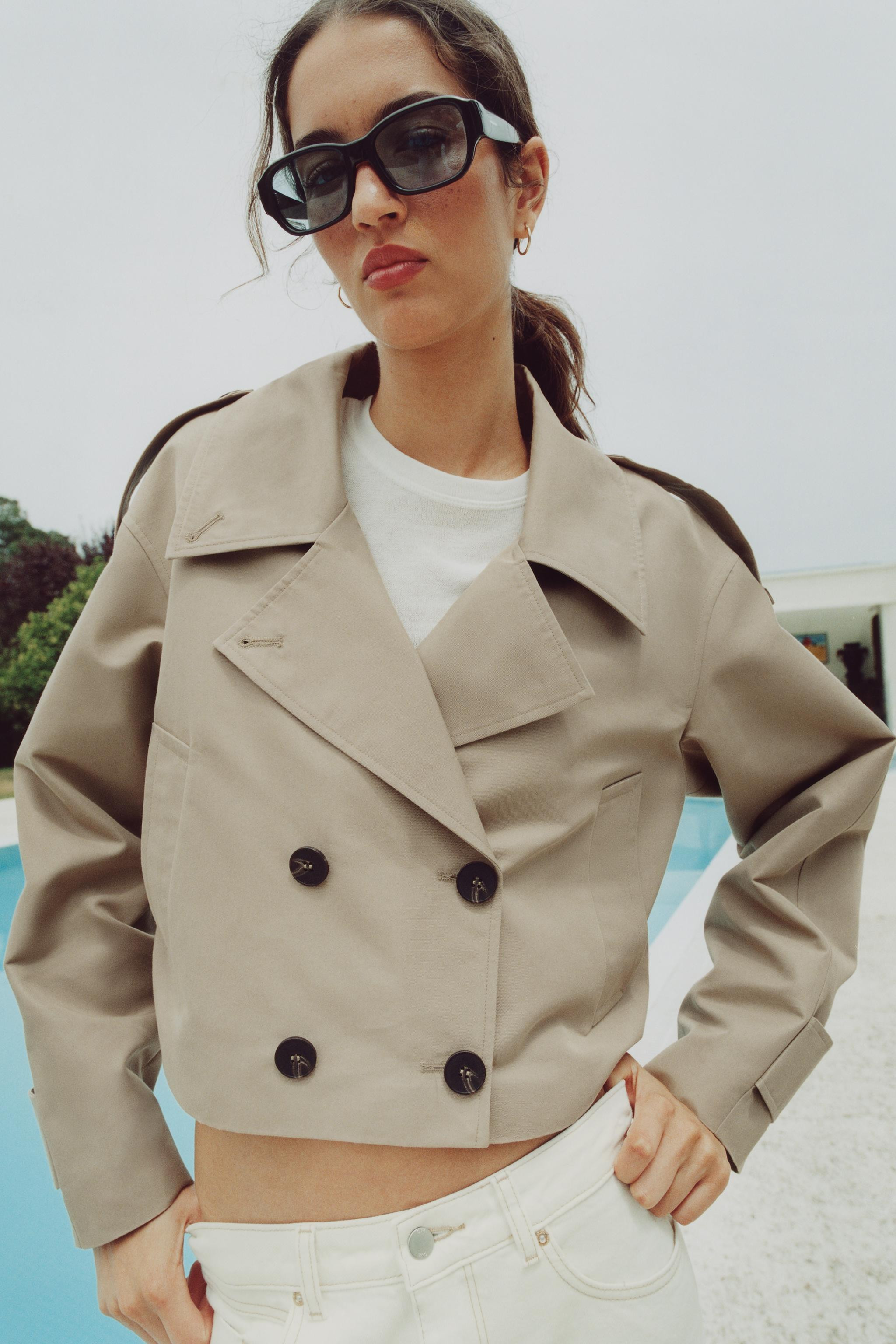 Short trench-style jacket with a lapel collar, long sleeves finished with a tab and button, front... | Zara US