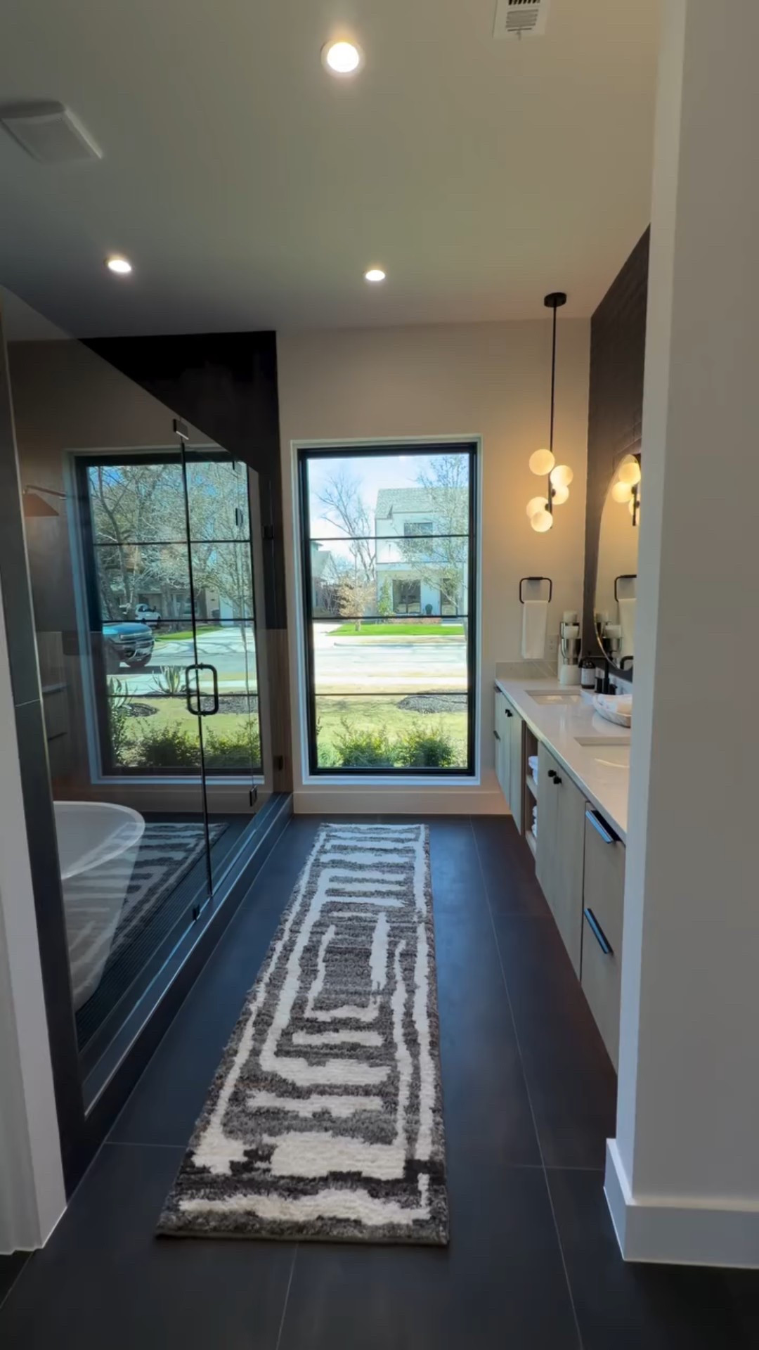 This primary bath design does it for me every time 🤌🏾🛁🫧

Moody dark tones layered with warm light woods, rich textures, and clean lines…Yum!! 

Every detail was intentional — from the contrast-driven palette to the sculptural moments that make the space feel elevated yet calm.
Soft. Sensual. Refined.
.
What do y’all think about this space… and that peek into the closet? 🤭✨