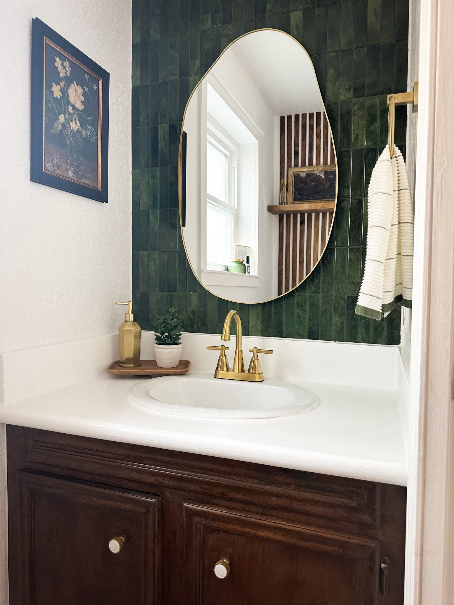 Powder room makeover with moody green tile, dark stained vanity, gold accents, and a mix of modern and traditional decor