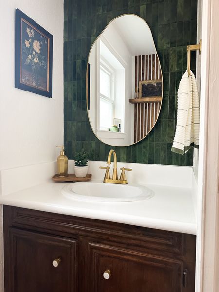 Powder room makeover with moody green tile, dark stained vanity, gold accents, and a mix of modern and traditional decor
