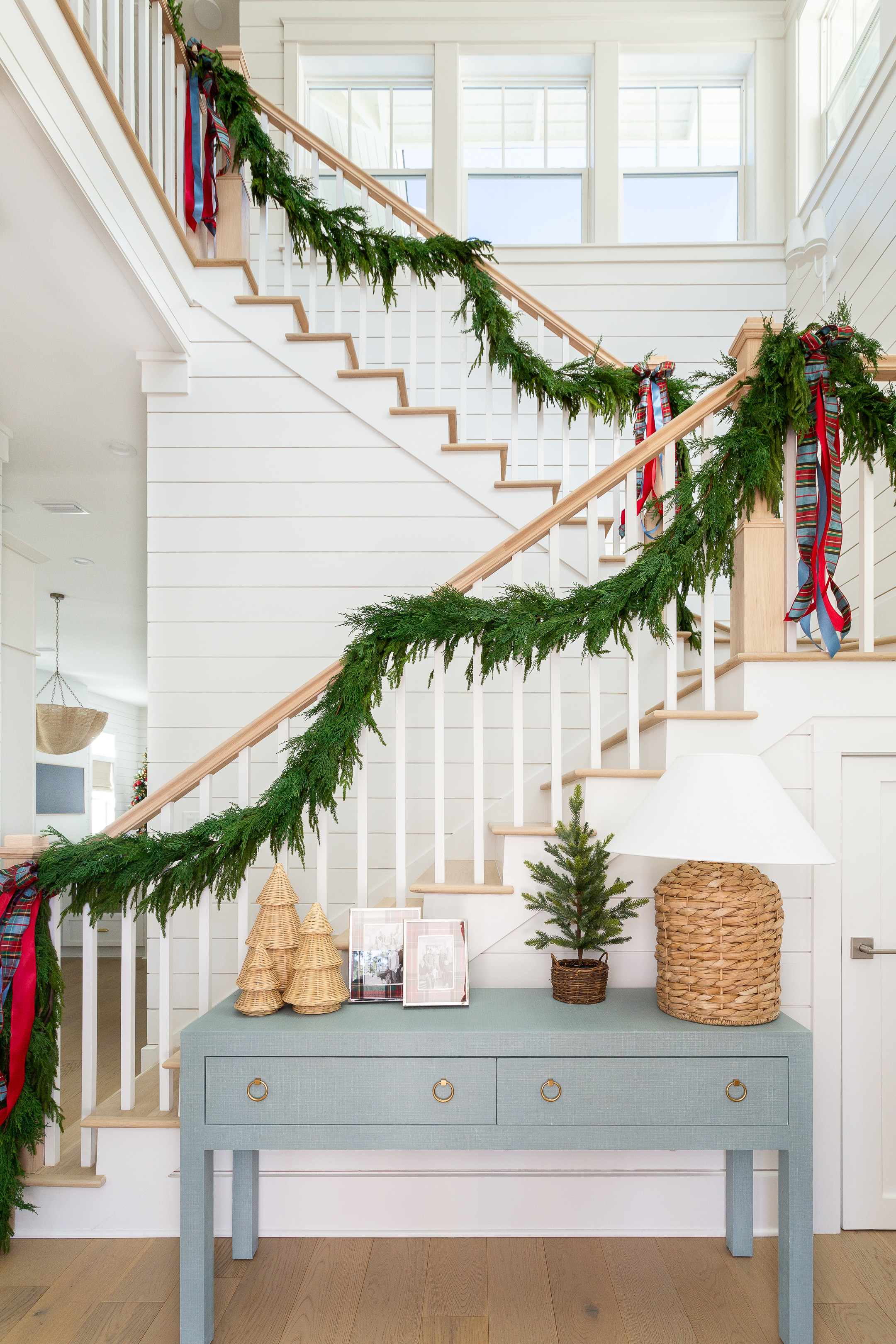Our coastal entryway decorated for Christmas with two types of garland (real-touch Norfolk pine and faux cedar), plaid bows, our blue linen console table, seagrass table lamp, wicker Christmas trees, Stewart plaid pictures frames, and a gold Moravian star chandelier. See our full Christmas home tour here: https://lifeonvirginiastreet.com/2024-christmas-home-tour/ #ltkholiday #ltkhome #ltksalealert #ltkfindsunder50 #ltkfindsunder100 #ltkstyletip #ltkseasonal 

 

#LTKHoliday #LTKHome #LTKSaleAlert