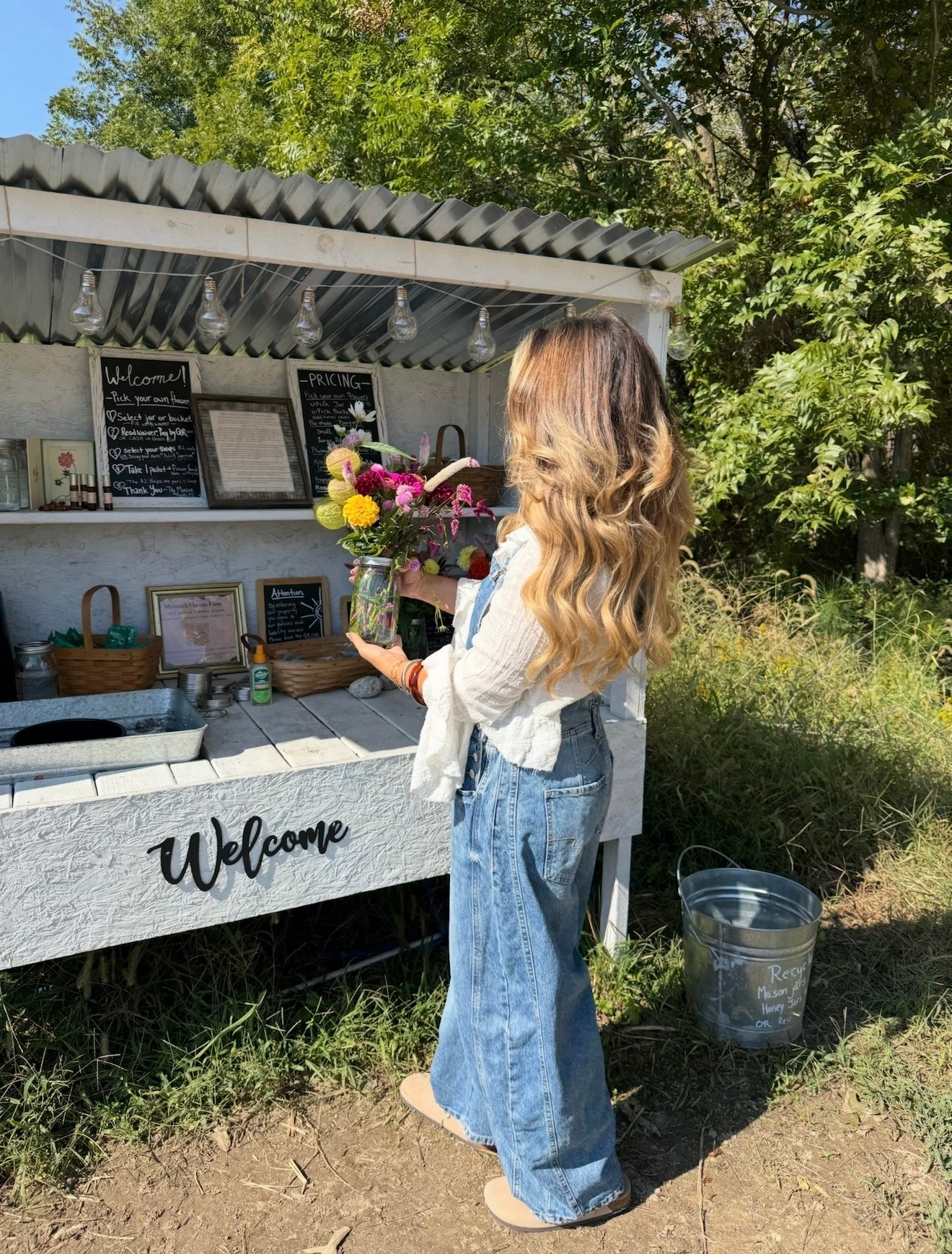 Easy fall outfit idea: baggy denim overalls, a white gauzy blouse, and suede clogs. Perfect for a flower farm day, pumpkin patch, or weekend errands. Petite-friendly overalls styling. Shop the look on my LTK.