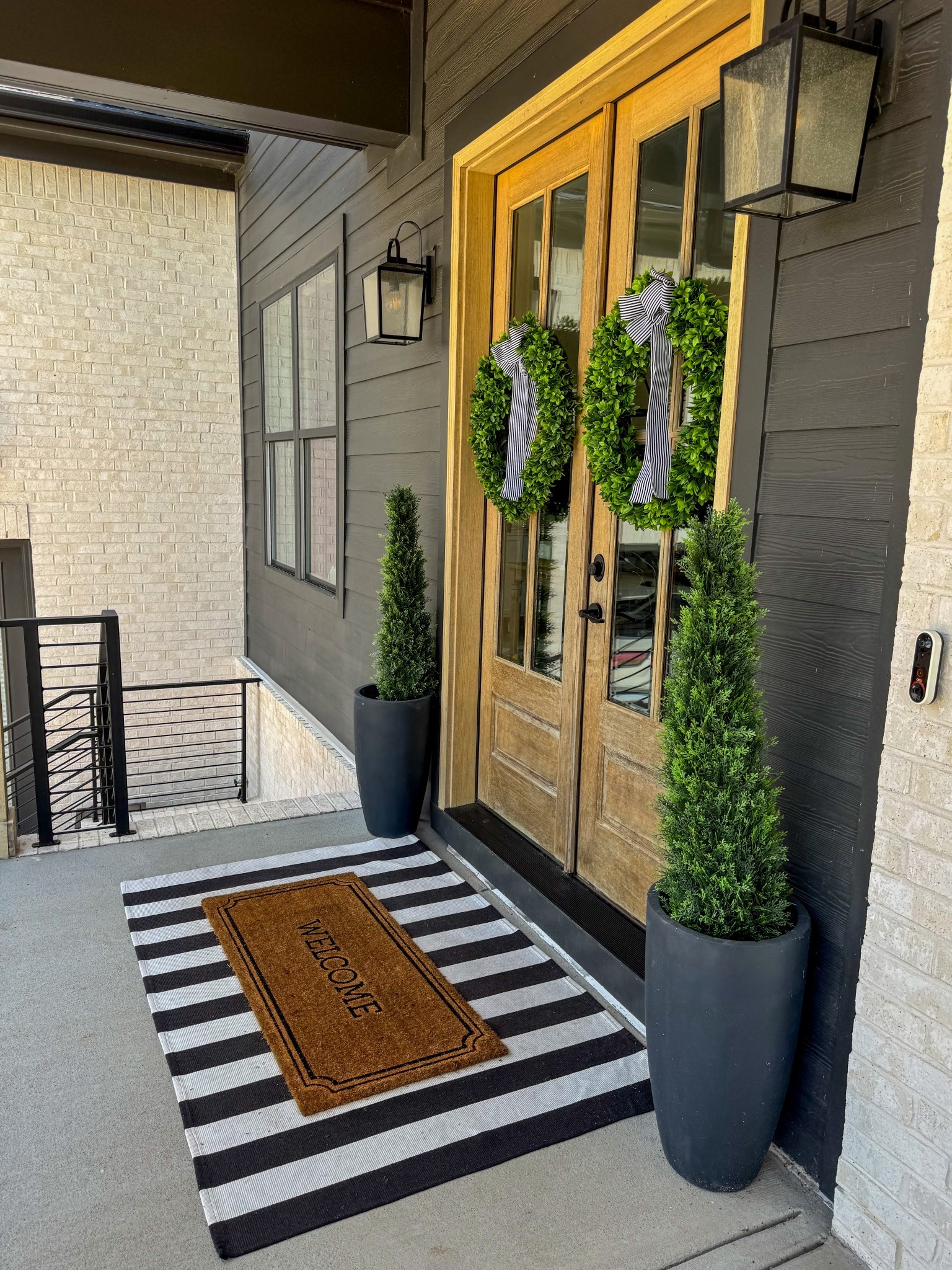 Front porch decor 🏡 
extra large striped outdoor welcome mat, 
faux topiary cedar tree outdoor plants, black planter, striped outdoor rug, welcome doormat, boxwood wreath, modern farmhouse front porch decor, outdoor entryway decor #frontporch 

#LTKHome