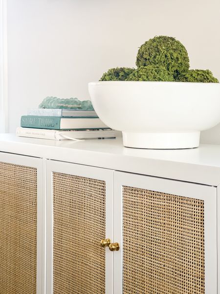 Finally working on decorating our Florida coastal cottage! In our living room, I’ve added this white and rattan cabinet for our media console, a oversized white ceramic footed bowl filled with moss balls, coastal inspired boiled, and some decorative recycled glass beads! .

#ltkhome #ltksalealert #ltkunder100 #ltkunder50 #ltkseasonal #ltkstyletip #LTKhome #LTKSeasonal #LTKunder50

#LTKunder100 #LTKhome #LTKsalealert