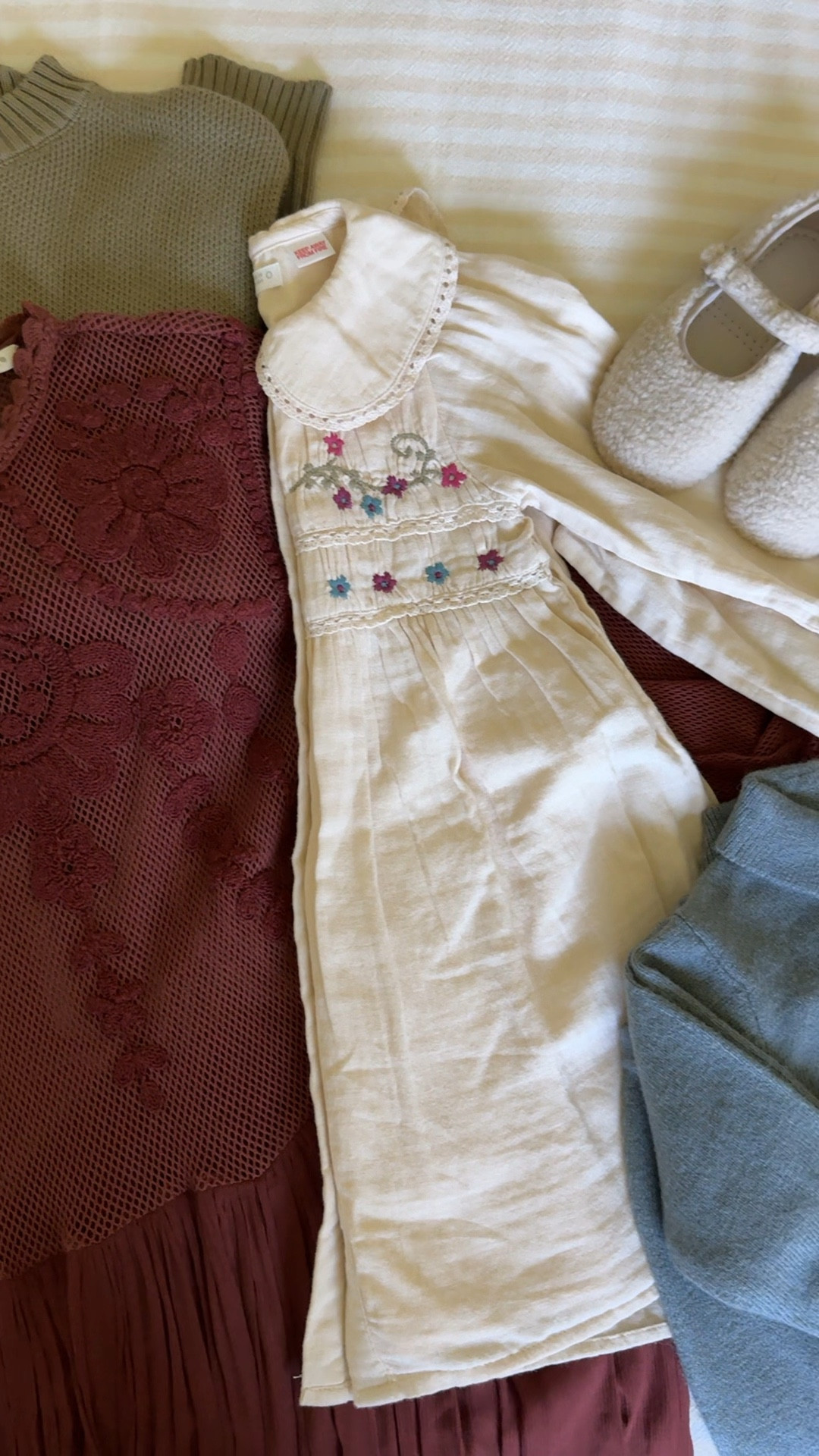 Coordinating outfits for fall family photos featuring warm, muted tones for fall and cozy textures. Embroidered little girls dress with flower, a see maroon embroidered women’s dress with eyelet detail, and blue sweater set for baby boy. 📸 
