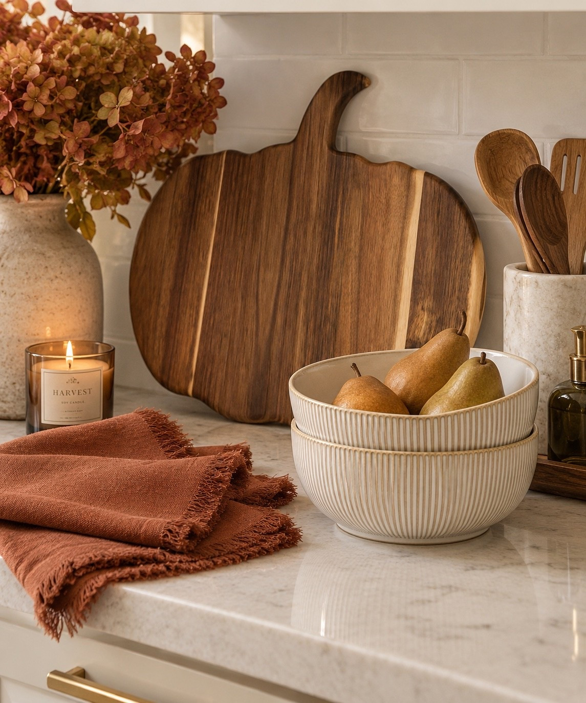 The easiest way to make a kitchen feel like fall without covering every surface in pumpkins. 🍂🤎 Warm wood, creamy ceramics and a little rust-colored linen bring in the season while still feeling neutral and elevated.

I love the pumpkin-shaped cutting board propped against the backsplash because it doubles as functional kitchenware and fall decor. Pair it with textured serving bowls and fringed napkins and you have pieces that can carry you straight through Thanksgiving. fall kitchen decor, fall kitchen ideas, neutral fall decor, neutral fall kitchen, cozy fall kitchen, warm kitchen decor, autumn kitchen decor, fall home decor, fall decorating ideas, subtle fall decor, elevated fall decor, classy fall decor, modern fall decor, transitional home decor, warm transitional decor, organic modern kitchen, cozy kitchen ideas, kitchen styling ideas, kitchen counter decor, kitchen countertop decor, kitchen counter styling, fall countertop decor, Amazon fall decor, Amazon fall finds, Amazon kitchen finds, Amazon home finds, Amazon home decor, pumpkin cutting board, pumpkin shaped cutting board, wood cutting board, decorative cutting board, cutting board decor, cutting board styling, wood kitchen accessories, serving bowls, ceramic serving bowls, ribbed serving bowls, neutral serving bowls, kitchen bowl set, rust napkins, terracotta napkins, cloth dinner napkins, fringed napkins, fall linens, Thanksgiving kitchen decor, Thanksgiving hosting, fall entertaining, fall hosting ideas, cozy home inspiration, Home and Behold

#LTKfoodie #LTKSeasonal #LTKHome