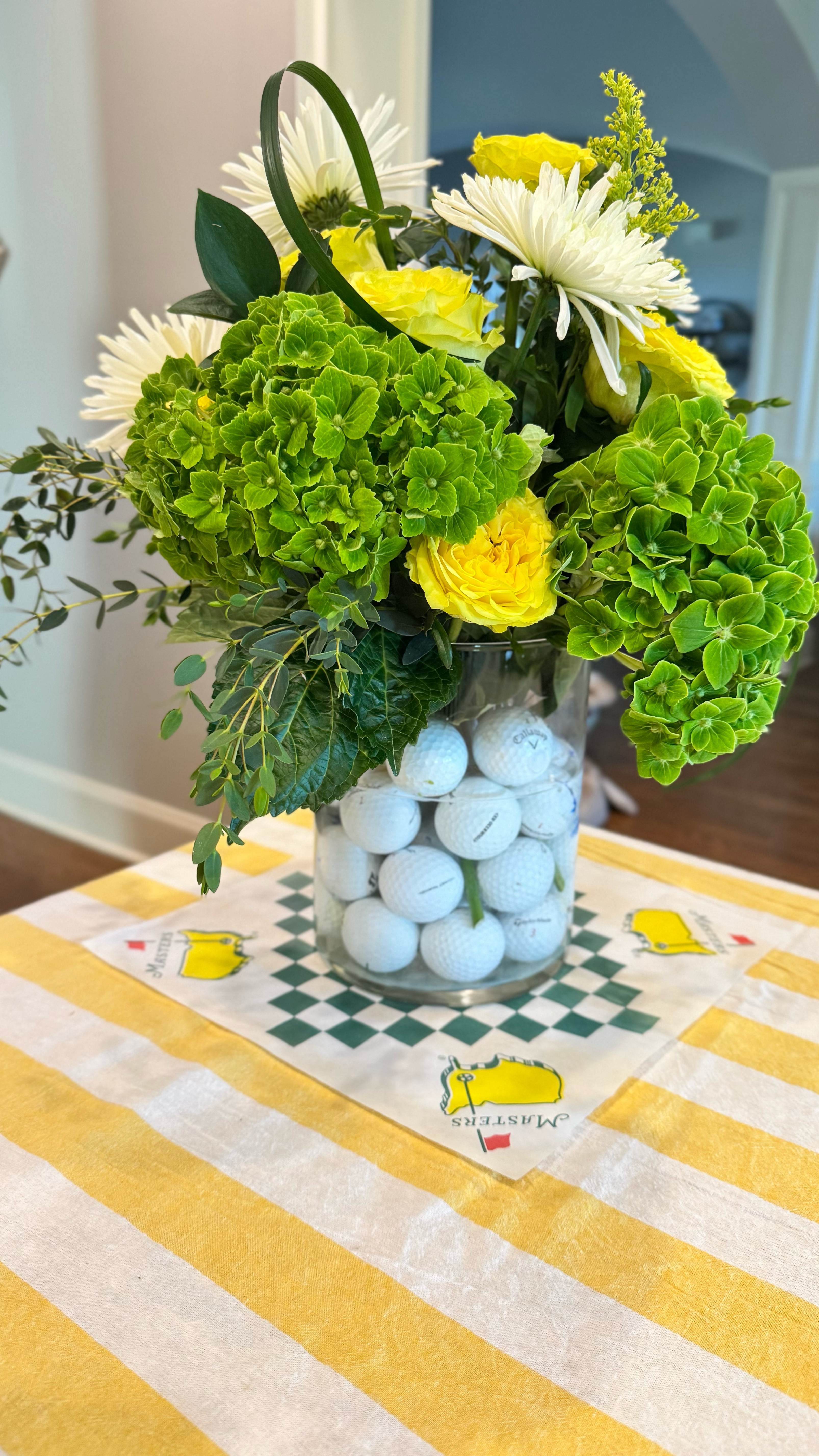 Inspired by the immaculate blooms and legendary landscapes of Augusta National. 

Start with your stars: crisp green hydrangeas that mirror Augusta’s lush greens, vibrant yellow ruffled roses for a pop of color, and white chrysanthemums for timeless elegance.

Pull your vase to the edge of the counter and hold each stem beside it. This makes it easy to cut each one to the perfect length—no guesswork.

Here’s a tip: make a 1-inch slit up the center of each hydrangea stem. This helps them absorb more water and stay full and perky longer.

I also like to “fluff” a few of my roses by twirling them. It makes them fuller and adds some additional Southern charm. 

What is your Master’s party must have? 

Follow for more easy, elegant DIYs and seasonal entertaining ideas—because the details matter! ⛳️

A simple, striking centerpiece inspired by Augusta—perfect for your Masters watch party, Sunday brunch, or spring table.

#MastersInspired #FloralDesign #SpringArrangement #HydrangeaHack #BoursinAndBlooms #TheMasters #GolfAndGarden #TraditionUnlikeAnyOther #easyentertaining #entertainingathome #entertaininstyle #entertainingessentials #mastersweek #themasters #augustanational #atraditionunlikeanyother 


#LTKFamily #LTKHome #LTKWatchNow
