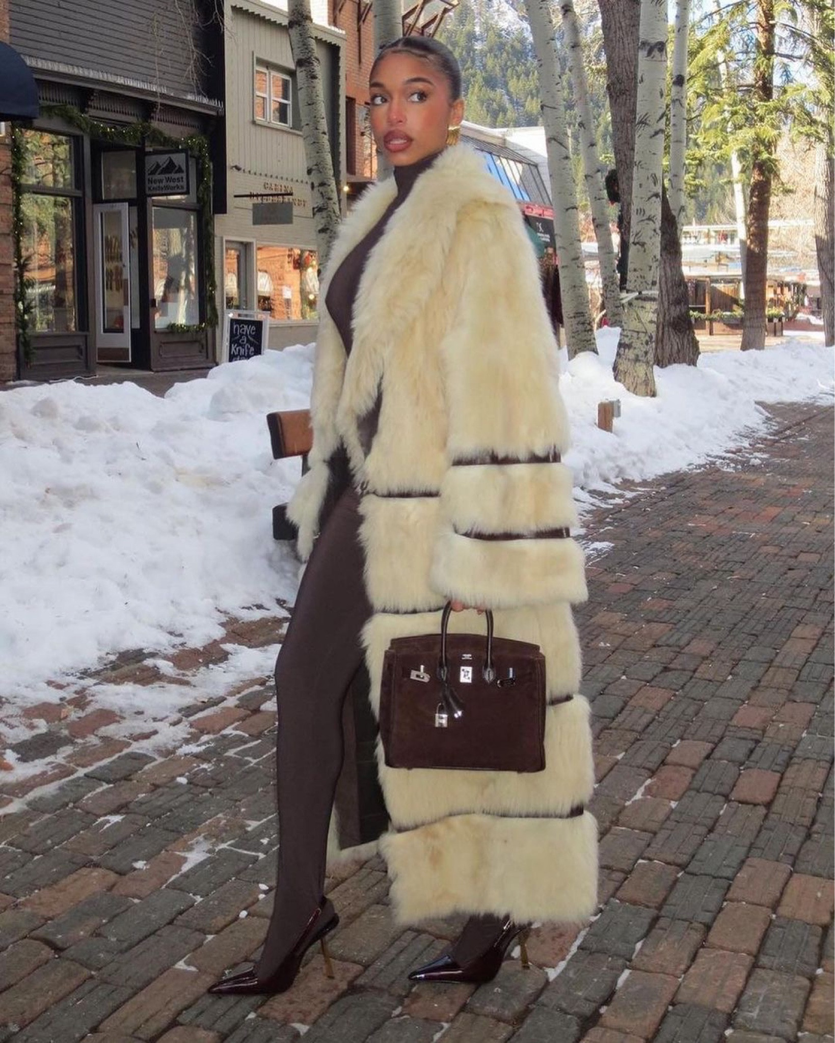 #LoriHarvey stepped out in Aspen wearing a $11,190 @khaite_ny Ada striped leather-trim shearling coat, a @normakamali chocolate onesie, @ysl sling backs, and a chocolate @hermes birkin bag. Thoughts? Shop #loriharveystyle at the link in bio! 📸Ig/Reproduction #loriharveyfbd