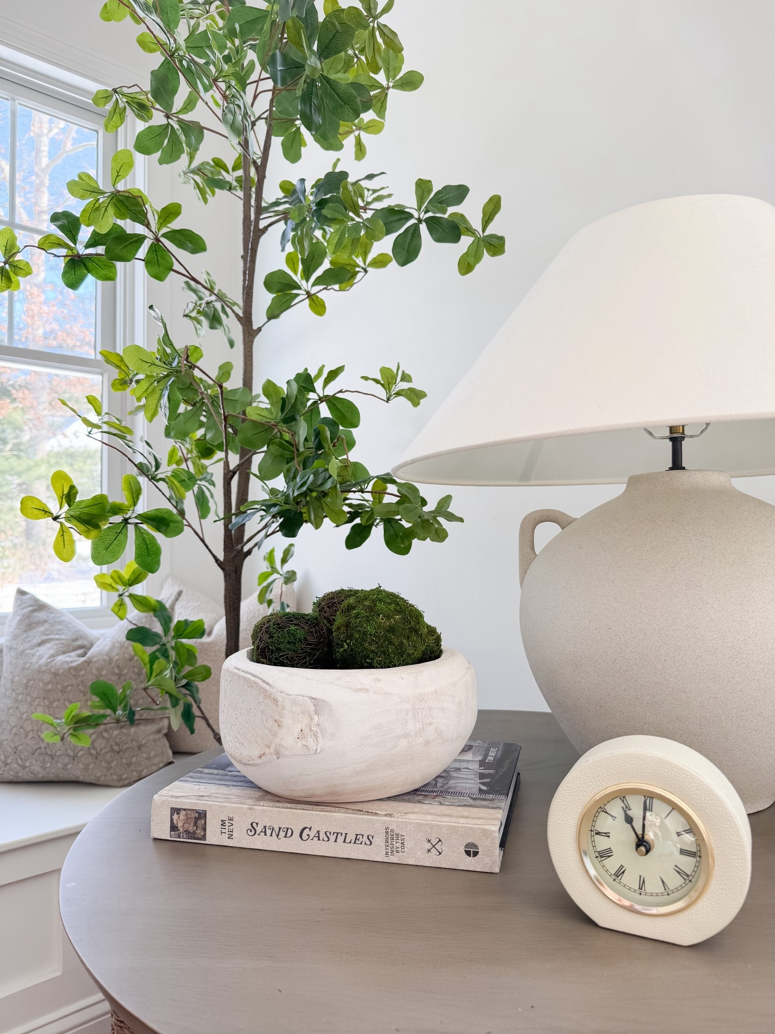 Cozy corner styling with round wood side table, oversized ceramic lamp, potted indoor tree, and textured neutral pillows. Simple spring refresh using natural materials and layered neutrals. 

#LTKHome