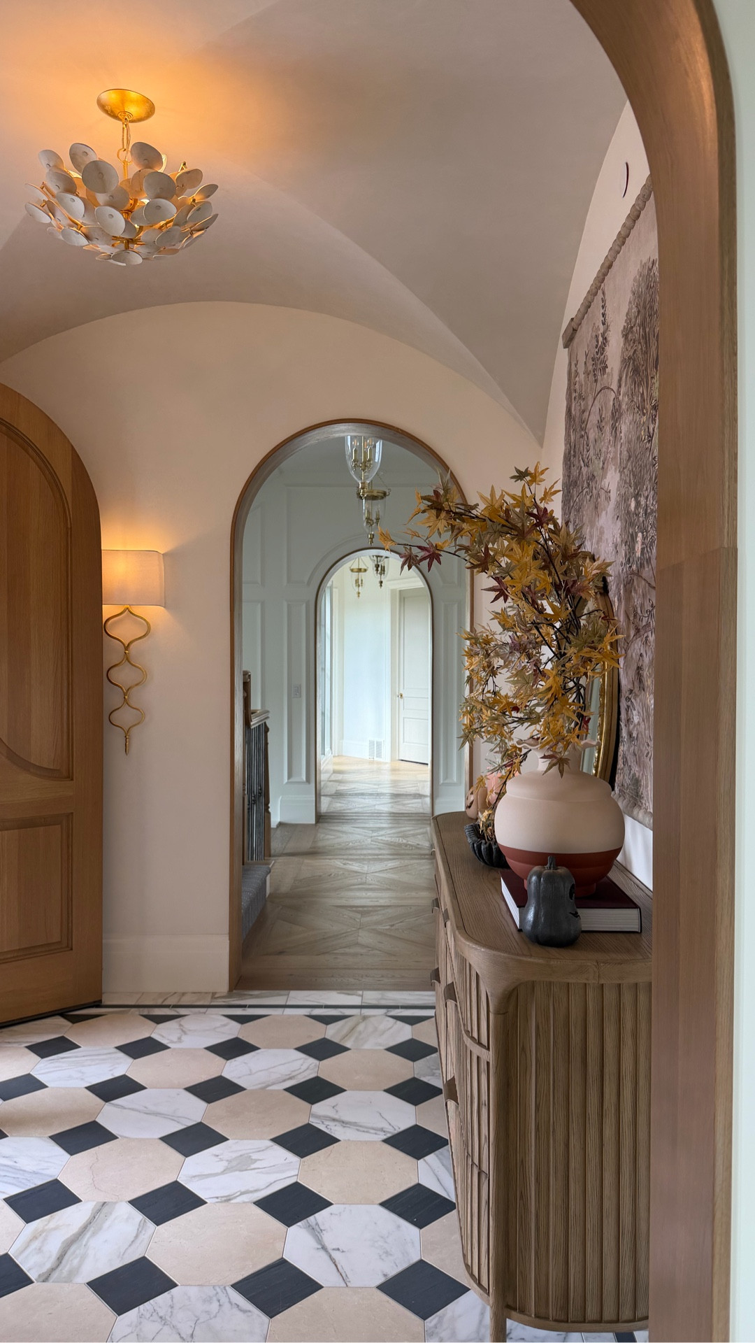 Traditional entryway with cathedral ceiling, fluted dresser, wall tapestry, gold wall sconces, semi flush mount chandelier, marble mosaic floor, Greek key door mat, realistic fall branches, ruffle vase, marble ruffle decor, pumpkins, real acorns and fall decor. 

#LTKSeasonal #LTKHome #LTKSaleAlert