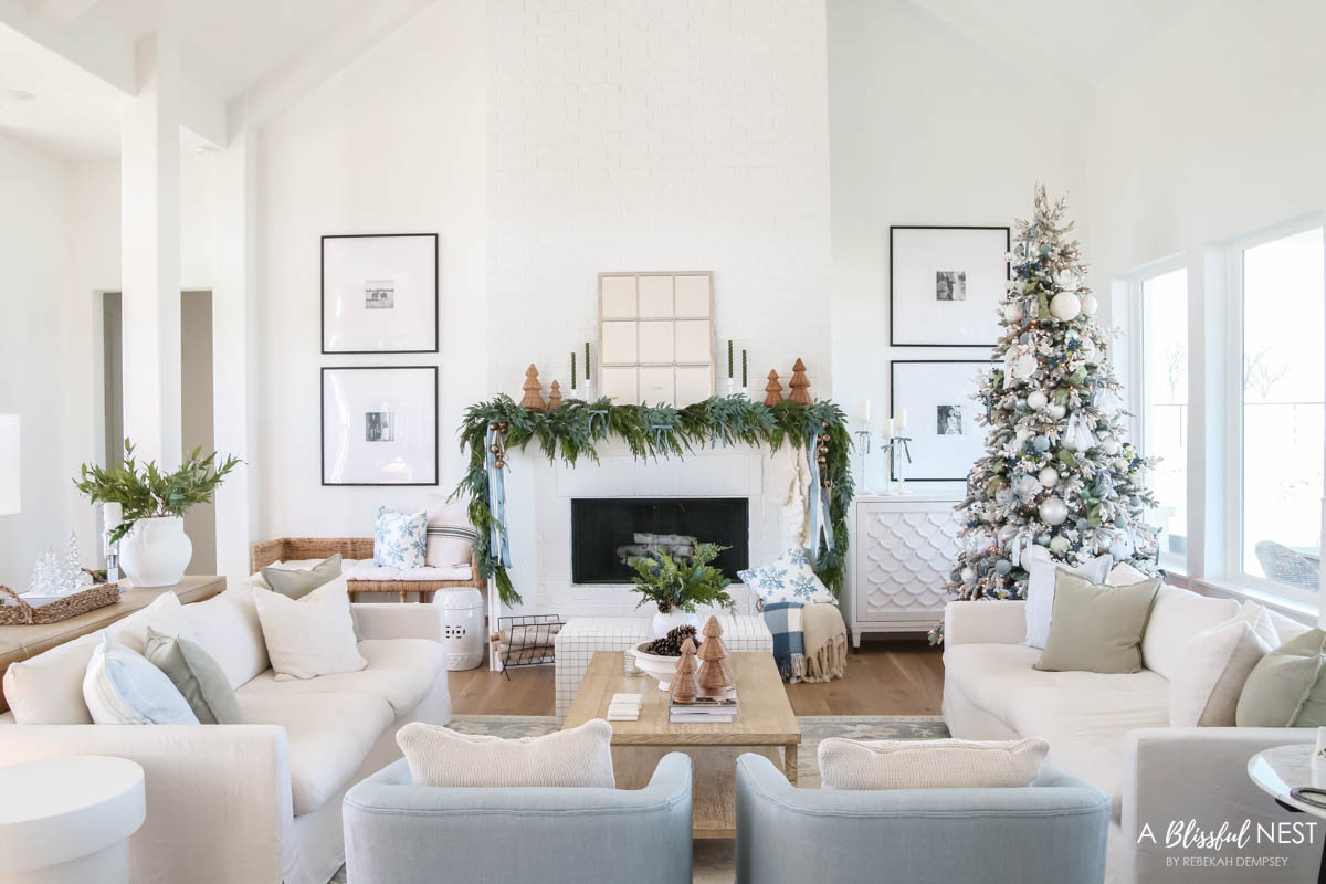 Bring simple holiday beauty to your living room. Shop the look now.
blue velvet bows, knit Christmas stockings, woven Christmas cone tree, norfolk pine Christmas garland, olive green taper candles, candlestick holders, dusty blue satin ribbon, ivory velvet ribbon, vintage cluster cow bells on rope, decorative birch logs, modern log holder, blue checkered throw blanket, upholstered cube ottoman, fairy lights, snowflakes decorative throw blanket, Christmas blue decorative pillow, natural pine cones, linen striped pillow, blue berry greenery picks, textured cream throw pillow, mercury glass finish Christmas tree decor, greenery stems, rattan tray, sky blue swivel chair, feather filled sofa, sage green pillow 

 #LTKHoliday #LTKSeasonal #LTKHome