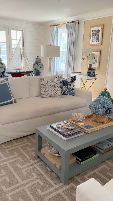 Blue, white, & coastal home decor and furniture in our living room 💙🤍🩵🌊… white slipcovered sofas, blue linen coffee table, blue and white pillows, blue and white jars, bamboo butlers tray, model sail boat, beach decor, grasscloth wallpaper, Burl wood picture frames, pottery barn sofa, custom blue and white curtains, Greek key rug, faux orchid, white garden stool, raffia tray

#LTKVideo #LTKhome #LTKover40