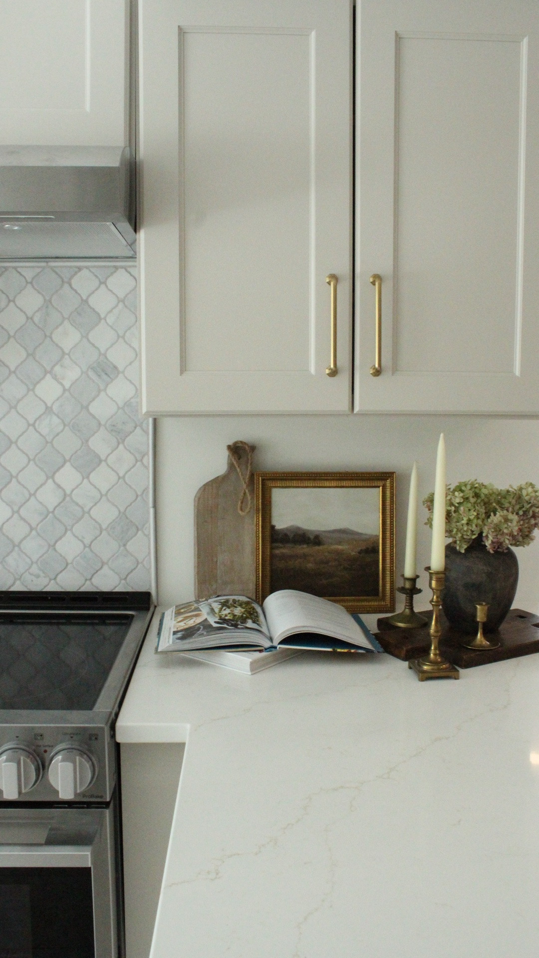 One of my favorite ways to make a kitchen feel warm and lived-in is by layering in those little everyday details that feel both functional and beautiful. A stack of cutting boards, vintage-inspired artwork leaning against the backsplash, warm wood utensils, brass candlesticks, little copper accents… it all adds so much softness and personality to a space without needing a full remodel.

I always love mixing practical pieces with decor so the kitchen still feels usable and relaxed instead of overly styled. These are the kinds of little finishing touches that make a kitchen feel cozy the second you walk in.

Everything linked here is inspired by this kitchen remodel I recently designed and styled for my clients. 

Tap to shop similar decor and styling pieces.

#LTKHome