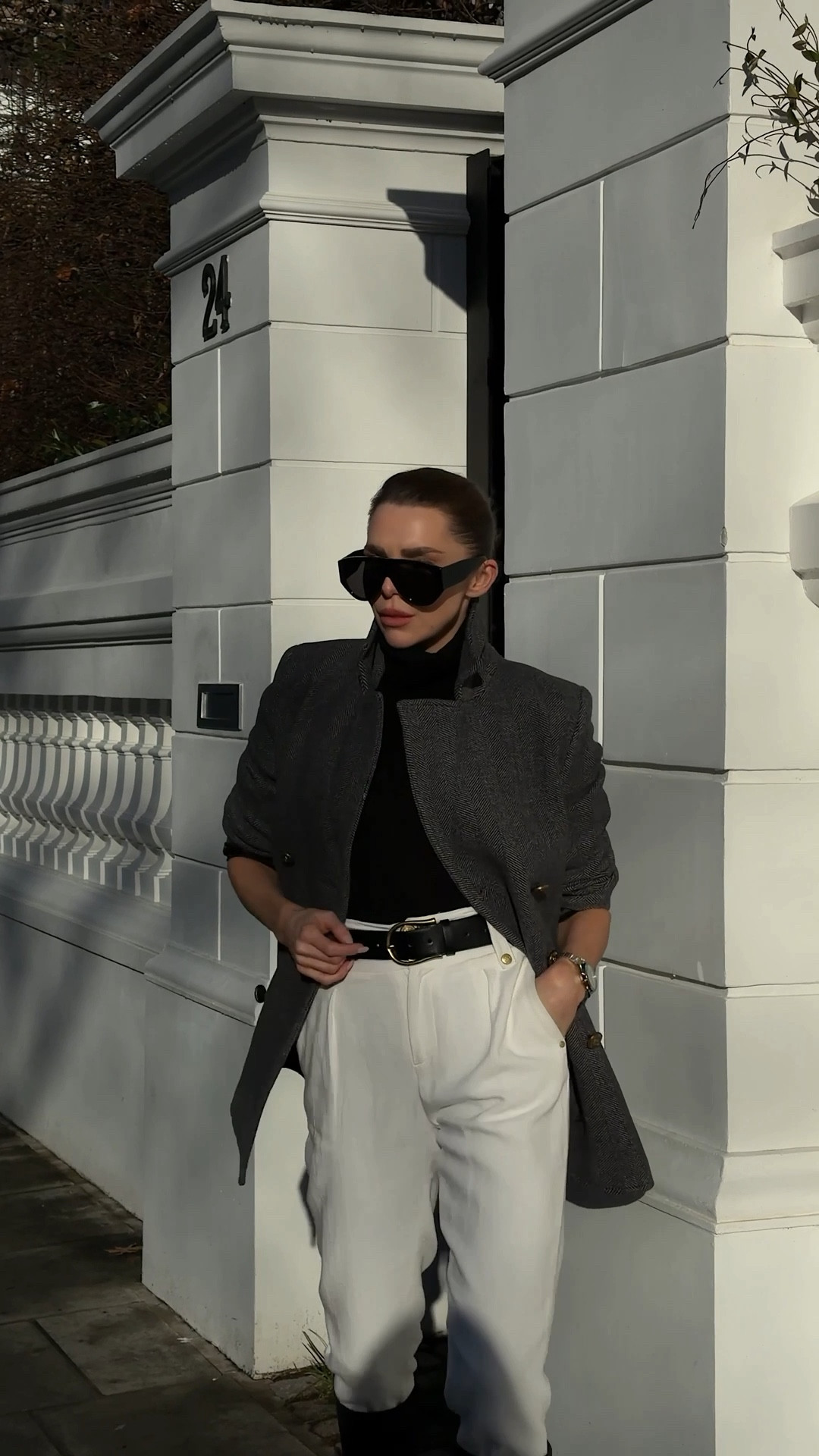 A classic grey wool peacoat styled over a black roll neck cinched at the waist with a belt, paired with white high-waisted tapered trousers for a clean, tailored silhouette. Finished with black suede ankle boots, oversized black aviator pilot sunglasses, and a structured black clutch bag for a timeless, elevated everyday look.

#LTKwinter #LTKuk #LTKeurope