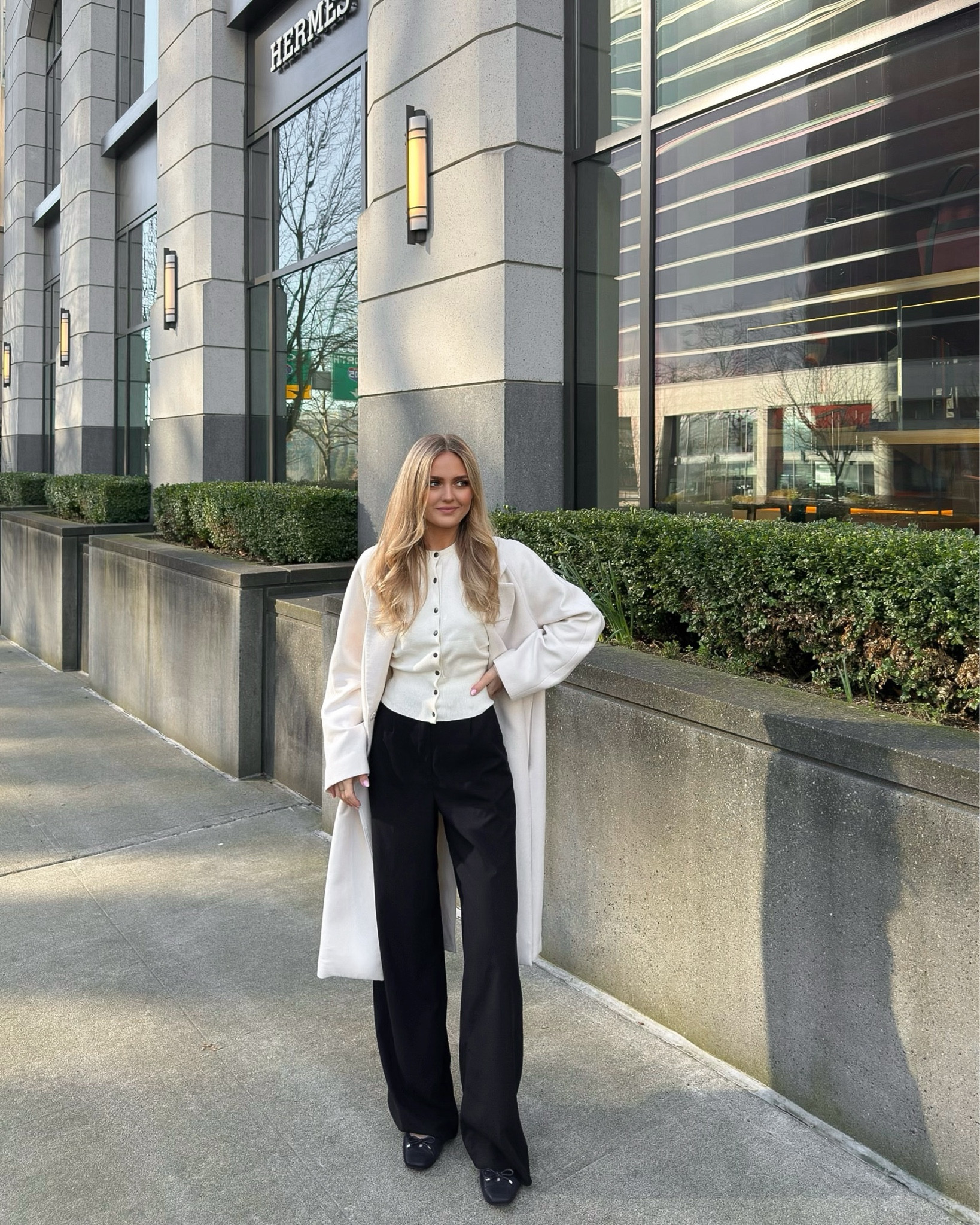 Black slacks, tall pants. White button cardigan. White shawl coat 