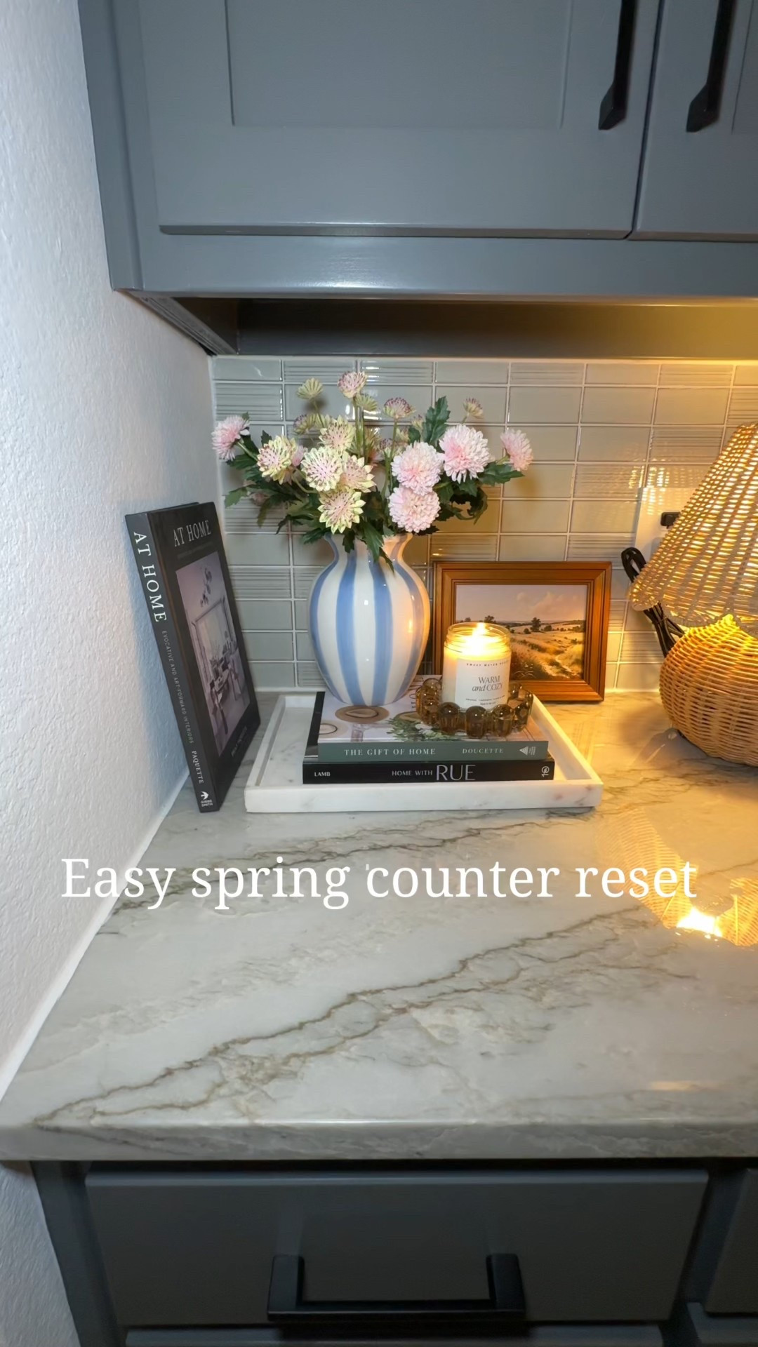 Spring counter styling ideas using affordable Target home decor featuring a viral rattan table lamp, neutral vase with realistic faux florals, decorative books, framed art, and cozy candle lighting for a warm layered kitchen look, modern neutral home decor inspiration, spring home refresh ideas, styled kitchen counter decor, cozy minimalist home styling, affordable spring home finds, neutral decor aesthetic, lived-in home styling tips, viral Target home finds, counter decor ideas for kitchens and coffee stations, transitional spring decor that works year-round.



#LTKFindsUnder100 #LTKstorytime #LTKHome