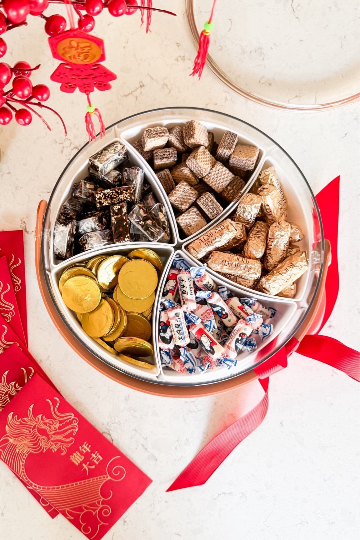 Lunar New Year Snack Tray! 
Divided serving tray with lid and handle, milk chocolate coins, Loacker Chocolate wafers, almond roca, white rabbit creamy candy, artificial plants, hanging pendants, brass vase

#LTKMostLoved #LTKhome #LTKSeasonal