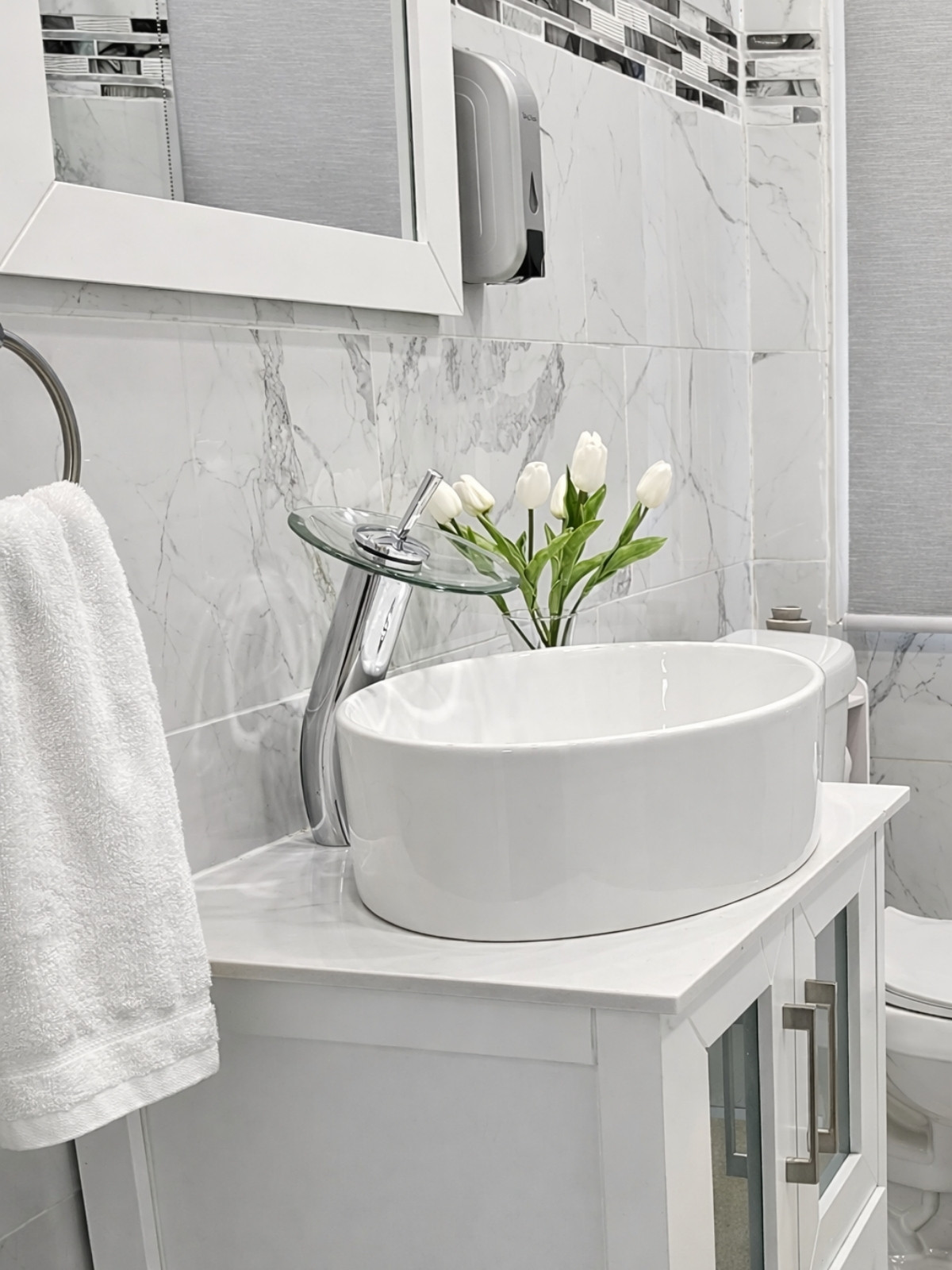 A pristine and modern bathroom setup featuring a sleek white vanity, elegant waterfall faucet, and ample storage solutions. Perfect for enhancing your bathroom's functionality and style. Everything linked below for you!🫶
 

 #LTKHome #LTKSaleAlert