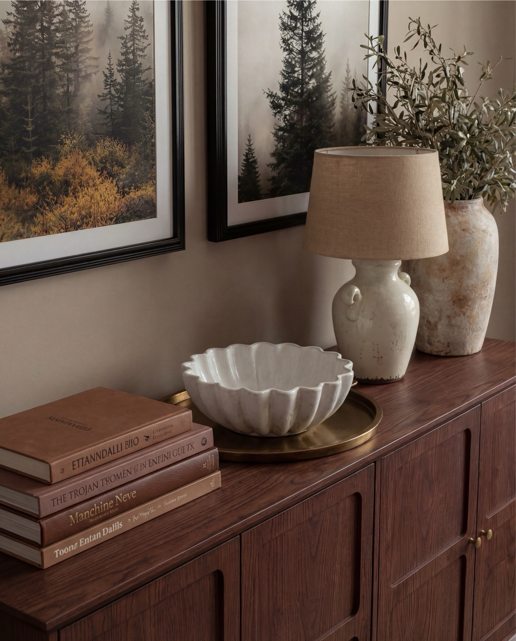 Shop the Look:
• Wood console table
• Framed landscape wall art (black frame)
• Neutral ceramic table lamp
• Stone or ceramic decorative bowl
• Large ceramic vase with faux olive branches
• Textured cube stools (neutral tone)
• Chunky knit throw blanket
• Neutral checkered patterned area rug
White flitted decor bowl
Brass oval serving tray
Brown decor books

#LTKSaleAlert #LTKHome