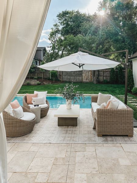 Embrace outdoor living with Pottery Barn styled patio space - featuring cozy seating spaces and oversized umbrella for entertaining all summer long 

Home finds, patio style, outdoor entertaining, wicker furniture, coffee table, umbrella faves, Pottery Barn style, neutral area rug, outdoor rug, pops of pink, faux olive branch, vase finds, neutral style, aesthetic home, summer entertaining, throw pillow, shop the look!