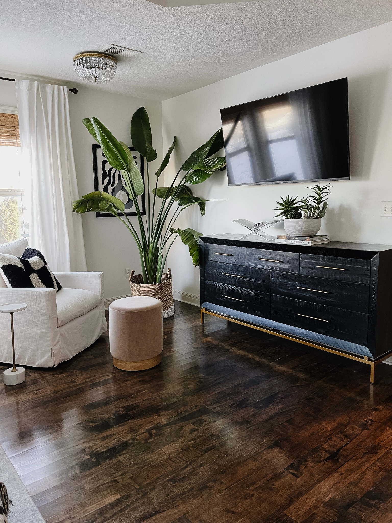 Corner styling in a bedroom, primary bedroom, master bedroom, black dresser, white upholstered swivel chair, velvet ottoman, black and white graphic pillow, acrylic book holder, marble drink table 

#LTKhome