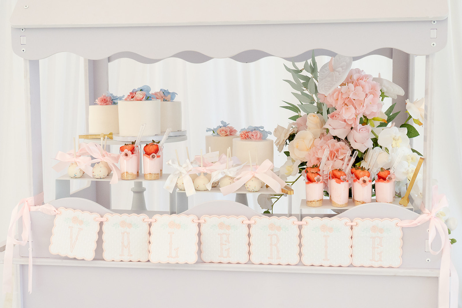 Our dessert cart was one of my favorite areas to style because it brought together so many thoughtful details.

We layered mini cakes, cake pops, fresh-inspired florals, elegant serving pieces, and a custom name banner to create a display that felt soft, timeless, and welcoming.

The personalized "Valerie" name banner and ribbons for the cake pops was handmade by us at Sol & Bella, adding a meaningful touch that made the dessert cart feel even more special. You can see more of our custom creations on Instagram @solandbella.

I've linked the styling supplies I used to create this setup if you're planning a baby shower or garden-inspired celebration of your own.

Save this collection for dessert table inspiration you'll come back to while planning. 

 #LTKBaby #LTKBump #LTKKids