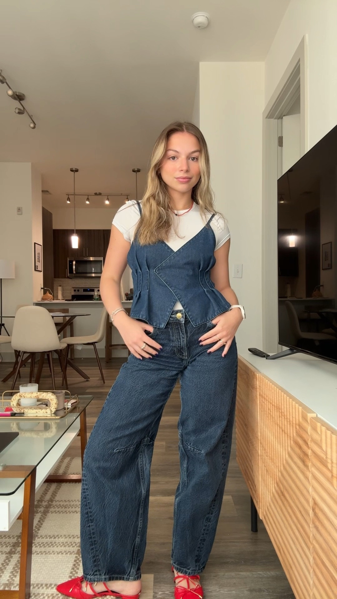 Denim on denim done right. A relaxed layered look with a white baby tee under a corset-style denim top and wide-leg jeans. Styled with bright red sandals for a pop of color. Perfect for effortless weekend outfits or casual nights out. Shop similar denim pieces, easy layering staples, and trending wide-leg jeans to recreate this look.