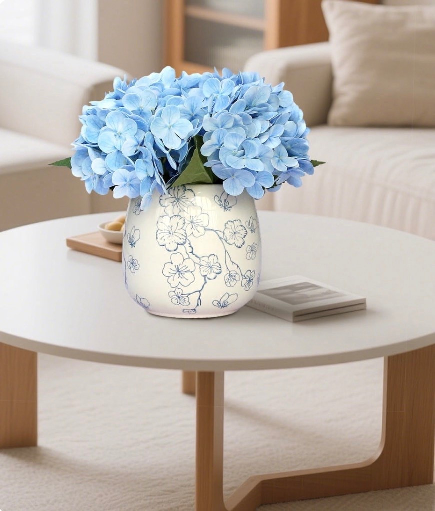 Adding a simple decorative lift to any room is easy with the My Texas House Faux Hydrangeas in Floral Vase, thanks to its compact size and pretty blue and white design. This 9.5-inch arrangement brings a fresh look to desks, shelves, entry tables, or kitchen counters without the need for upkeep. The full hydrangea petals create a lifelike shape that works well on its own or as part of a larger display. The coordinating floral vase adds an elegant touch and blends smoothly with a variety of decor styles, making it a versatile accent for your home. You can place it in smaller spaces or use it to brighten a room with a light, cheerful feel. The My Texas House Faux Hydrangeas in Floral Vase is a lovely choice for refreshing your home this season.

#LTKHome #LTKSeasonal #LTKmorningroutine