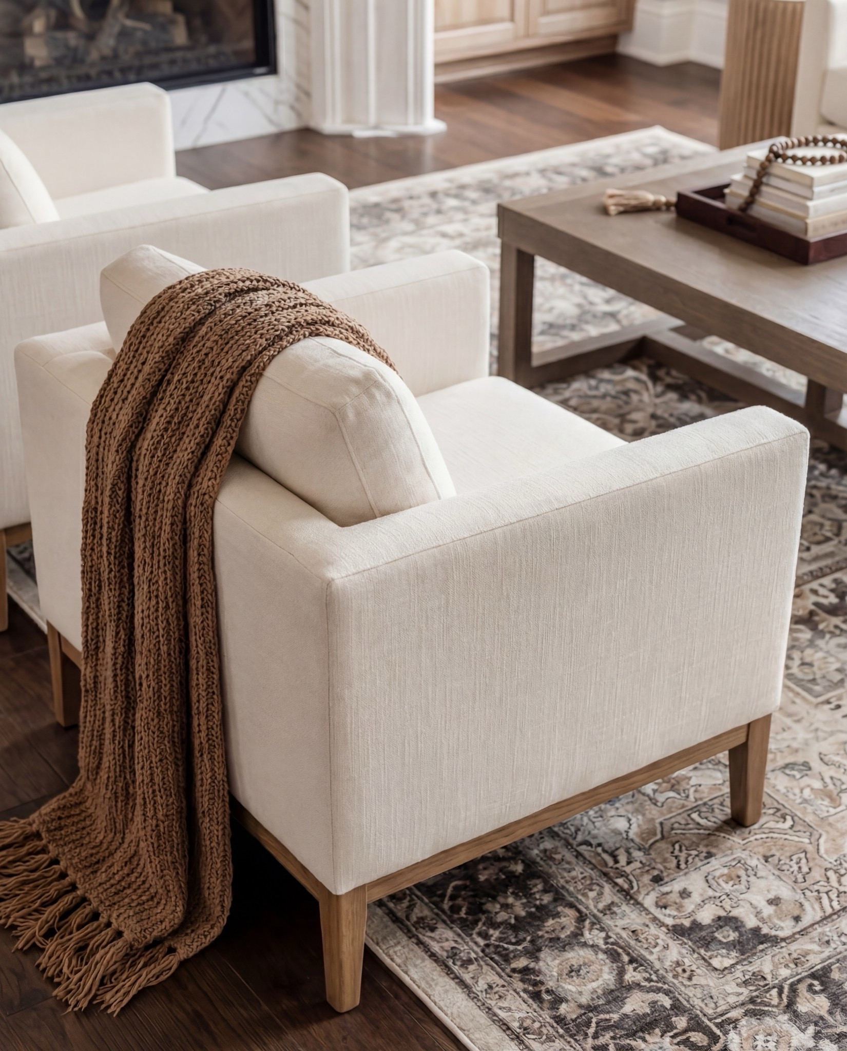 Shop the Look:
• Cream upholstered sofas
• Upholstered accent chairs (clean, modern arms)
• Marble-look fireplace décor
• Solid wood coffee table
• Neutral vintage-style area rug
• Large ceramic jug vase
• Wood + ribbed side tables
• Warm wood built-ins (or shelf styling accents)
• Throw blankets in warm caramel tones
• Neutral patterned pillows



#LTKHome #LTKSaleAlert