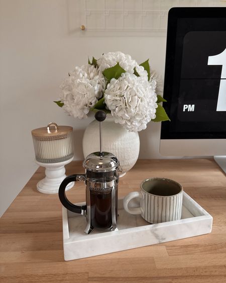 A little pic I snapped while working from home! I love having a cozy desk setup. This Amazon marble tray has been used in so many ways in my home! From holding perfume, to displaying coffee syrups, to catching my miscellaneous jewelry. Right now I have it sitting on my desk & I like to place my coffee there. I have recently been trying to cut back on my caffeine, so when I am craving coffee later in the day I will use my French Press to make decaf coffee! I pour it into my cute, green striped Hearth & Hand Magnolia Mugs from Target that are so perfect for spring.
I also have this gorgeous ribbed vase from Target filled with faux hydrangeas! These flowers are so budget friendly, but still look real! I have two packs in this photo. Next to the vase I have a marble candle holder (here is a similar one) with a candle on top. I like to keep my desk pretty simple and I love the look of this corner!
And, of course, I could not be organized without my acrylic calendars hanging behind my desk! The perfect work from home setup!


Target finds, amazon home, amazon decor, target decor, fake flowers, desk decor, office decor, office inspiration 

#LTKhome