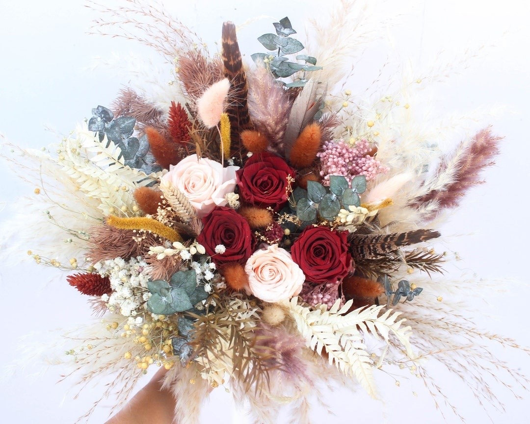 This stunning dried flower bouquet features preserved maroon and peach roses, soft pampas grass, eucalyptus, fern leaves, bunny tails, pheasant feathers, and delicate wildflowers in elegant neutral tones. Perfect for brides and bridesmaids, this handcrafted arrangement offers timeless beauty and a soft romantic feel that can be treasured long after your wedding day. Finished with a blush pink ribbon and available in bridal and bridesmaid sizes. #DriedFlowerBouquet #PreservedRoseBouquet #BridalBouquet #BridesmaidBouquet #WeddingFlowers #BohoWedding #EverlastingFlowers #NeutralWedding #RusticWedding #LTKWedding

#LTKSeasonal