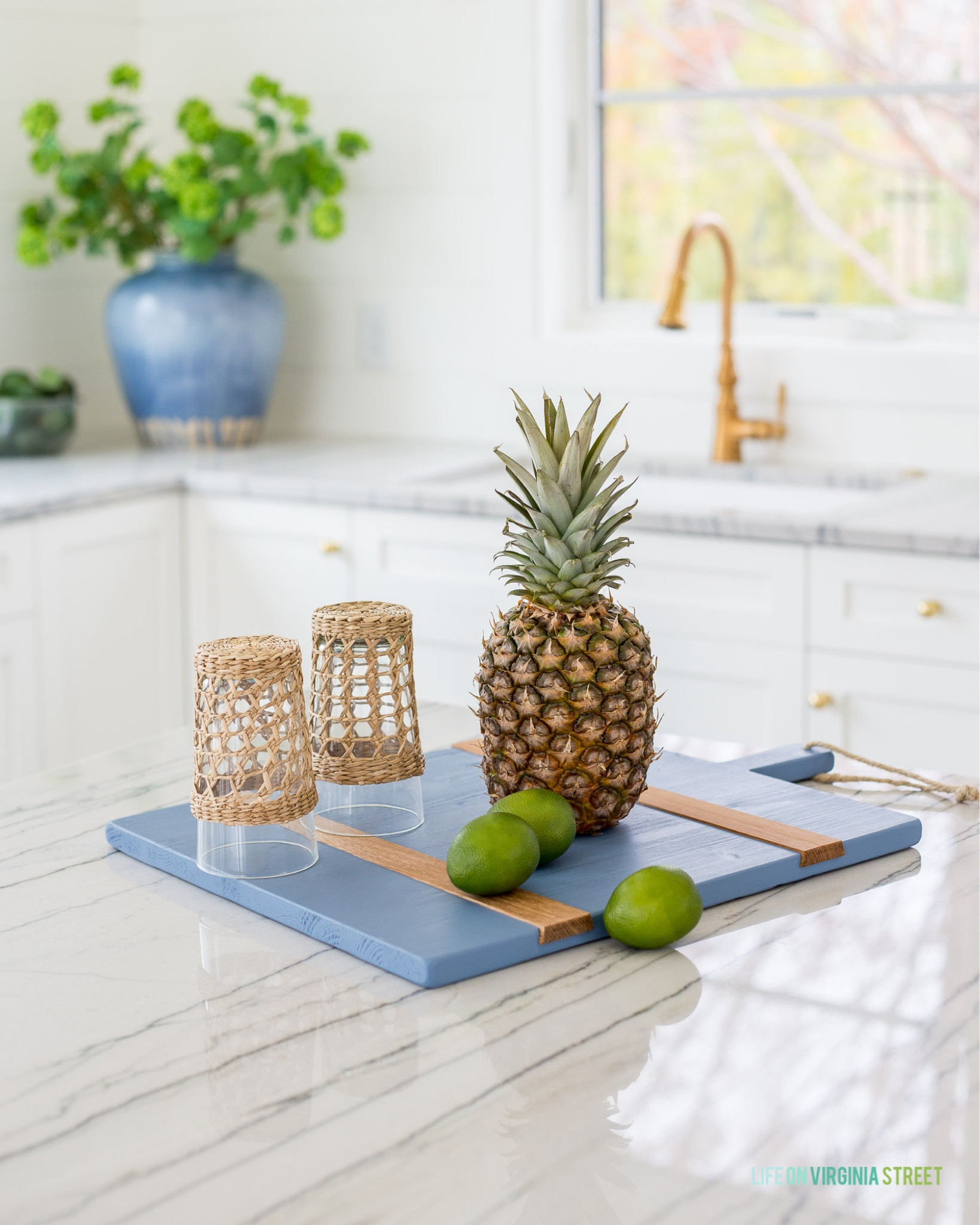 A closeup look at our quartzite countertops in our pool house kitchen! Style with a blue charcuterie board, cane wrapped glasses, a large blue ceramic vase, faux viburnum, and a gold kitchen faucet and cabinet hardware.
.
#ltkhome #ltksalealert #ltkseasonal #ltkunder50 #ltkunder100 #ltkstyletip #ltkfind

#LTKSeasonal #LTKhome #LTKsalealert