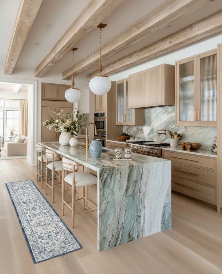 A light and elevated kitchen that pairs natural warmth with serene sophistication.
Soft oak cabinetry and exposed beams set a grounded foundation, while the striking blue-green marble brings organic movement and quiet luxury. The waterfall island and matching backsplash create a seamless, sculptural statement — perfectly balanced by warm brass accents and globe pendants.

Textural bar stools, fresh florals, and a vintage-inspired runner add softness and soul, turning this modern kitchen into a welcoming, layered gathering space. 

#LTKSaleAlert #LTKHome