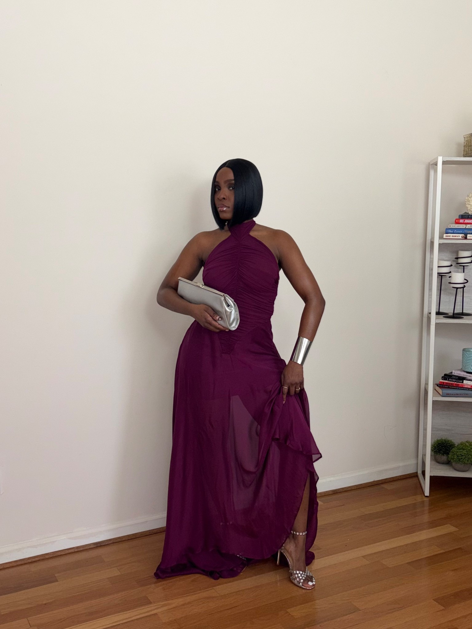 Plum halter neck gown
Burgundy halter dress
Ruched evening dress
Sheer overlay maxi dress
Floor-length formal gown
Draped bodice dress
Body-skimming eveningwear
Elegant sleeveless gown
Silver clutch bag
Metallic statement cuff bracelet
Minimal accessories styling
Sleek bob hairstyle
Polished glam beauty look