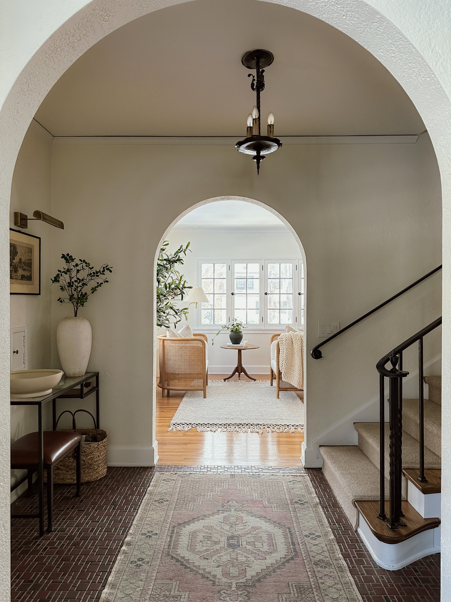 entryway foyer and living room room sitting area details. battery operated sconce, vase, area rug, cane chairs, pedestal table, faux plants, decorative bowl, knitted blanket, pleated shade floor lamp, 

#LTKhome