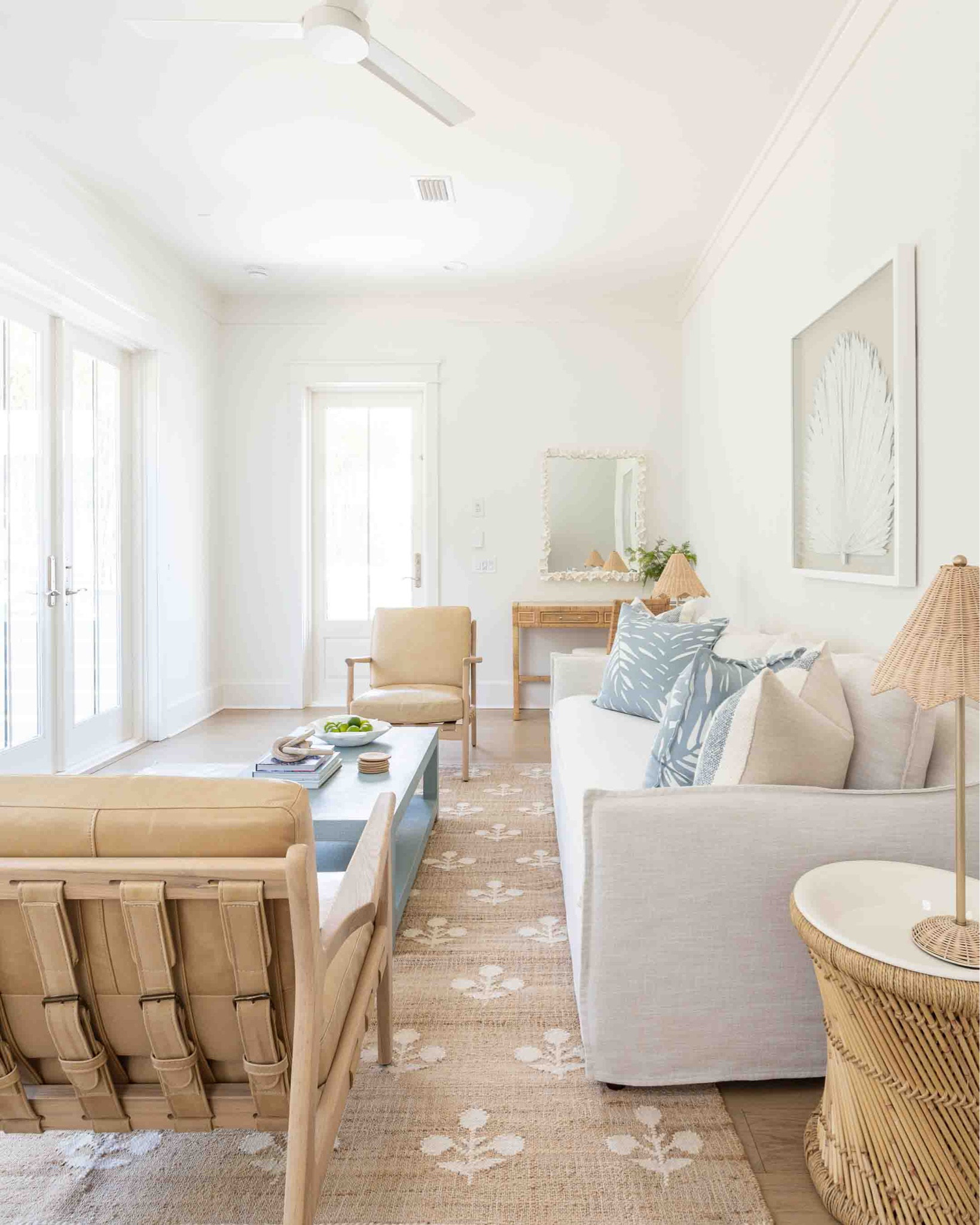 Our Florida carriage house living room features a slipcovered indoor/outdoor sofa, camel leather chairs, block print rug, a light blue coffee table, scalloped rattan lamps, round side tables, oversized palm art, and light blue tropical pillows! I love our white coral mirror hanging over this affordable rattan desk, too! Take the full tour here: https://lifeonvirginiastreet.com/our-florida-carriage-house-tour/.
.
#ltkhome #ltkseasonal #ltksalealert #ltkfindsunder50 #ltkfindsunder100 #ltkstyletip #ltktravel #ltkover40 coastal living room decor, Serena & Lily style, coastal grandmillennial, coastal grandmother aesthetic 

#LTKSeasonal #LTKsalealert #LTKhome