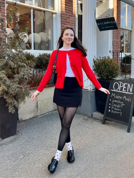 Valentine’s Day outfit with red cardigan, tights, black skirt, heart socks, and black loafers