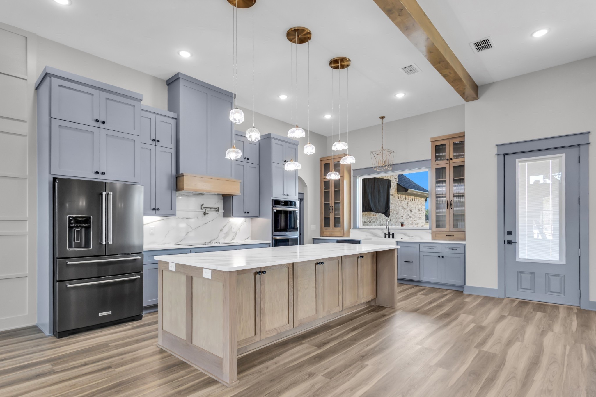 Modern farmhouse kitchen with soft blue custom cabinets, white oak island, and Taj Mahal style countertops 🤍✨ I linked the glass globe pendant lights, stainless steel refrigerator, cabinet hardware, double wall oven, Delta kitchen faucet, farmhouse sink, and Delta pot filler for you.

This space was designed to feel warm, functional, and high end perfect for everyday living and entertaining. Save this for kitchen inspo if you love clean lines, mixed wood tones, and timeless finishes.

#LTKhome #KitchenDesign #ModernFarmhouse #KitchenInspo #CustomHome #WhiteOak #DeltaFaucet #PendantLighting #NewConstruction #TylerTXHomes