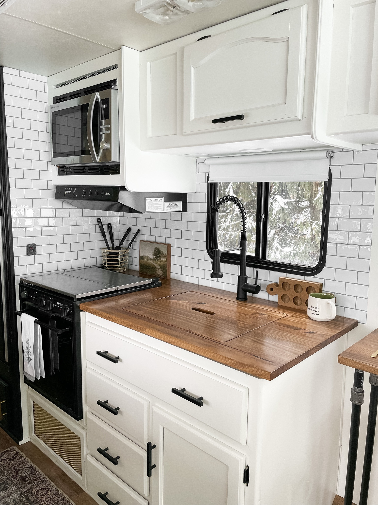 RV kitchen renovation.  White kitchen cabinets, peel and stick subway tile.  Black kitchen hardware.  Black modern faucet.  Amazon landscape art.  Stainless steel kitchen farmhouse sink.  

#LTKunder100 #LTKhome #LTKfamily