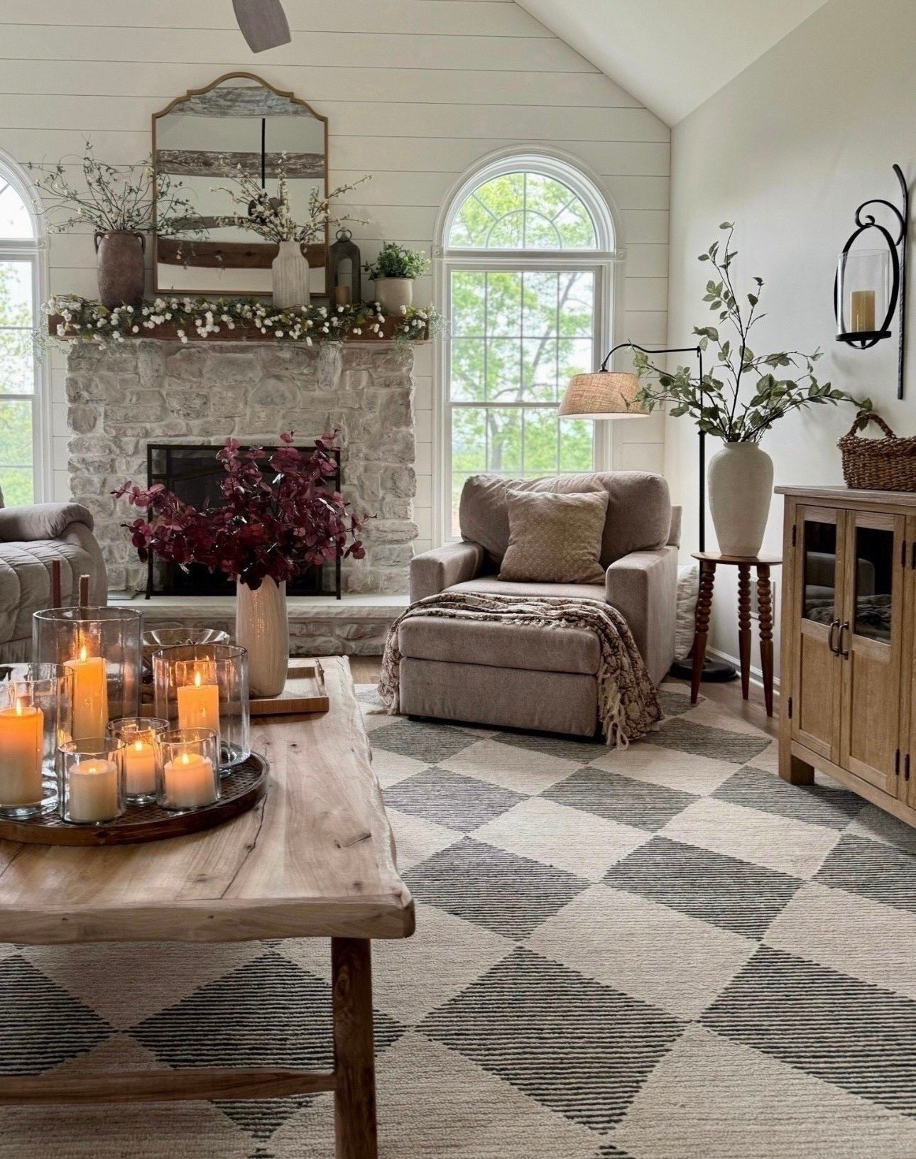 Curved arm floor lamp with linen shade is back in stock and on sale. Solid wood accent table and buffet table. Custom made reclaimed wood coffee table. Charcoal and beige geometric rug. Glass hurricane candle holders in 3 sizes. Tall sage green stems. Very popular cascading cream hops florals on top of fireplace, handcrafted metal lantern is back in stock. The best burning wax pillar candles and brown vintage floral throw. Neutral accent chair from Best Home Furnishings. 