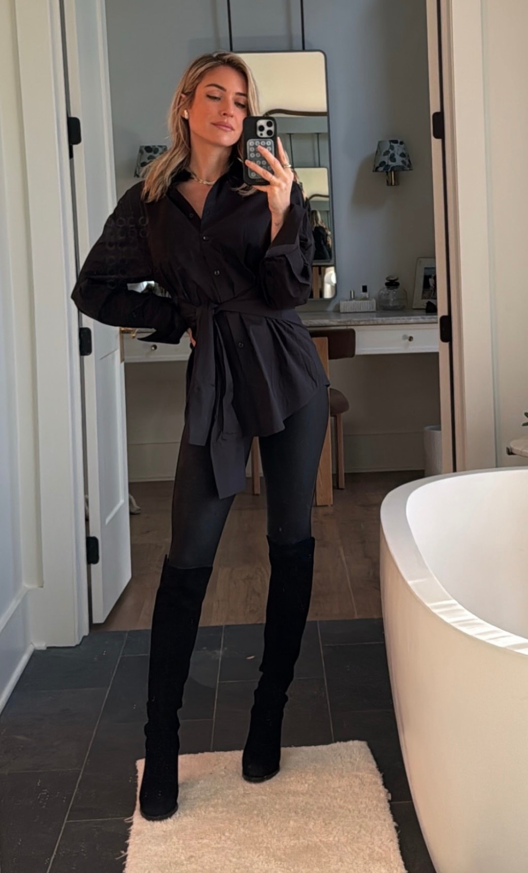 Kristin Cavallari's black Cotton poplin top in black. Features an adjustable tie waist for a customizable fit. A versatile piece designed to dress up or down. Black leggings,  mixed metal jewelry and suede over the knee boots 