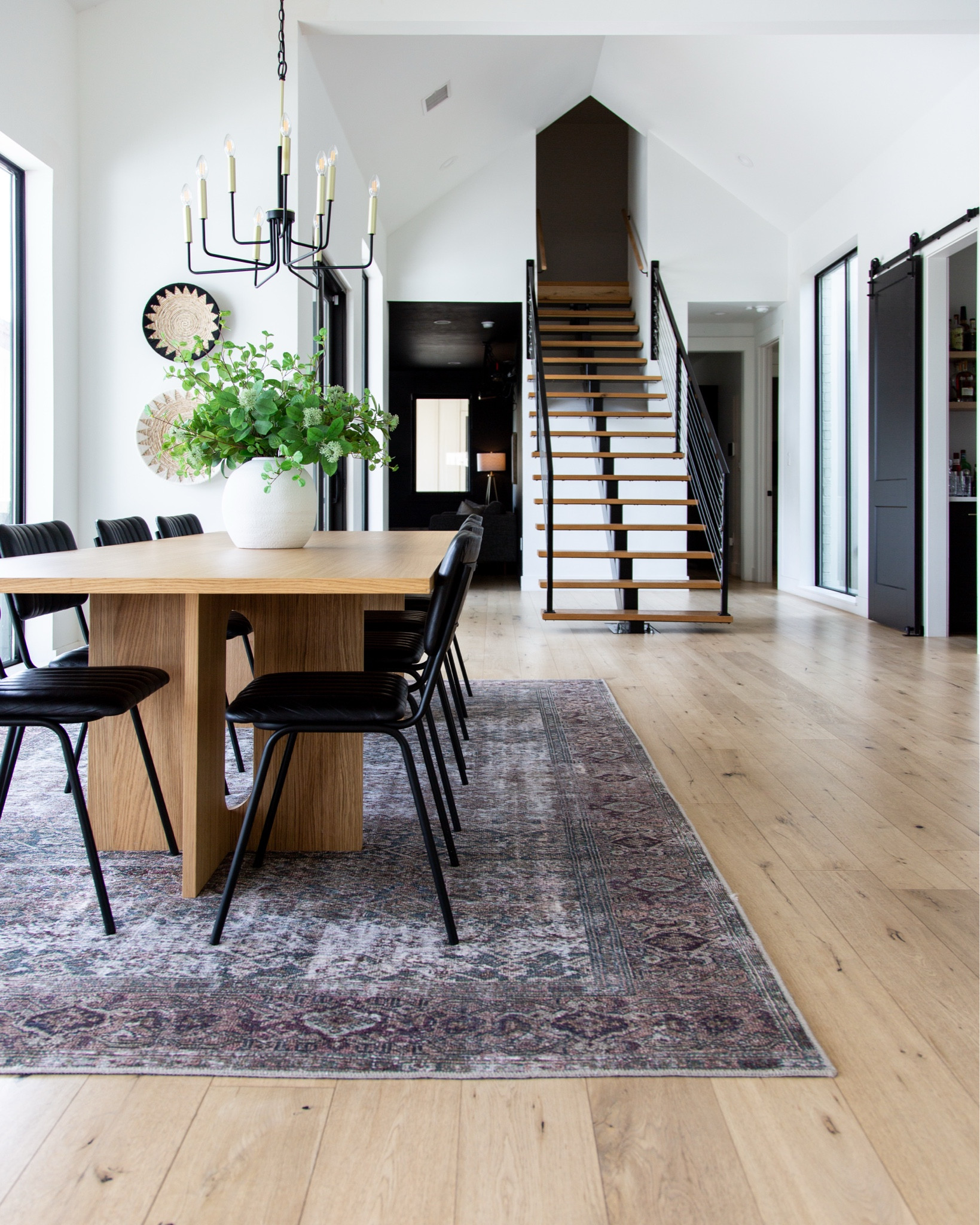 Our dining room is one of my favorite spaces for gathering, and it’s all about the thoughtful decor details. The natural wood dining table brings warmth and texture, paired with sleek black chairs for a modern contrast. The vintage-inspired rug anchors the space and adds a layer of character and depth. On the table, a large vase filled with fresh greenery keeps the space feeling vibrant and welcoming. The black chandelier is a bold yet timeless statement piece that ties everything together, while the woven wall decor adds an extra layer of personality. It’s a space that feels both functional and styled, perfect for everyday meals or hosting family and friends.


#LTKSeasonal #LTKFamily #LTKHome