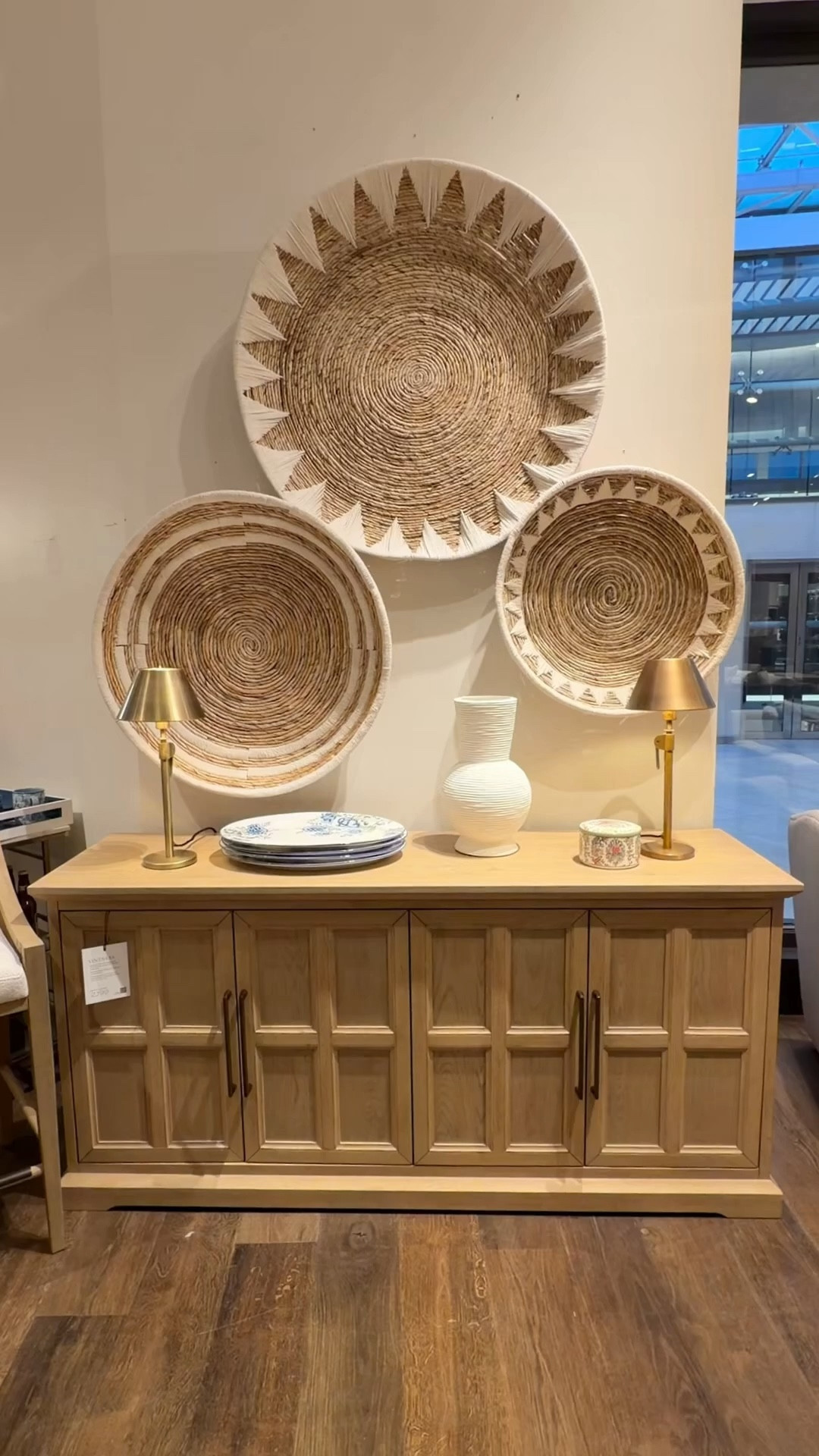 A beautiful balance of craftsmanship and character! 😍 The Vintners Buffet from Pottery Barn stands out with its warm Savanna finish, tailored geometric door detailing, and antique brass accents. 🤎✨ It anchors the room with a refined, neutral presence and offers generous concealed storage to keep everything organized behind closed doors. Styled here with the Sunny Handwoven Basket Wall Art (Set of 3) in Natural/White above, it creates a layered look that feels collected and thoughtfully curated! ☀️ A designer-inspired sideboard moment that feels both classic and contemporary—polished, warm, and effortlessly elevated! 💫 #PotteryBarn #DiningRoomInspo
#Sideboard 

#LTKHome #LTKSaleAlert