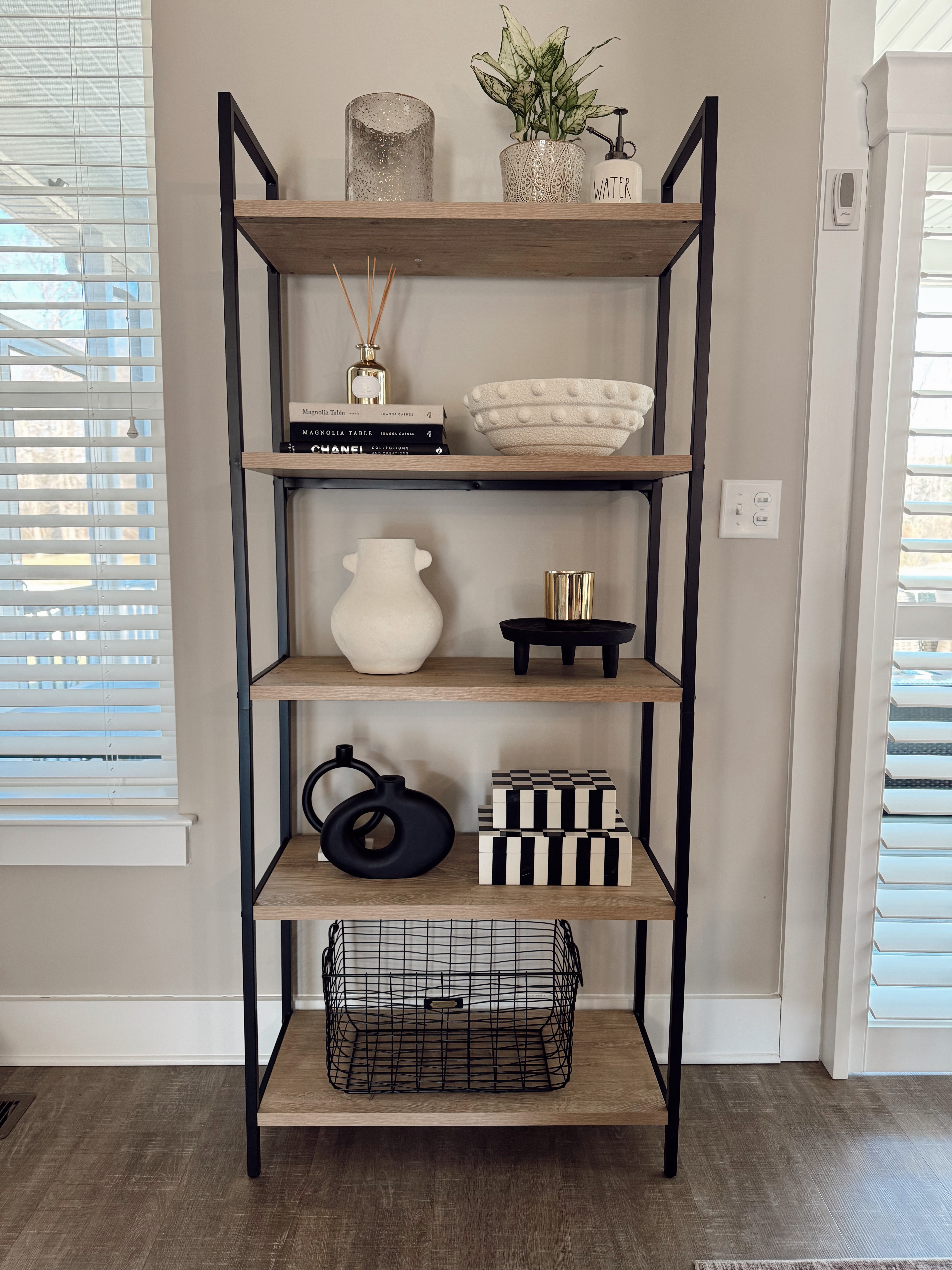 How to decorate a shelf: black and white neutral style. Most of my items I found in store at Home Goods but linked what I could or similar. White vase, white ceramic decor bowl, black donut vases (which I'm obsessed with!), black riser with gold accent candle, reed diffuser, real plant with Rae Dunn ceramic watering can, black wire basket, decorative fashion books, and black and white accent boxes. Home decor, bookshelf, style a shelf 

 

#LTKHome