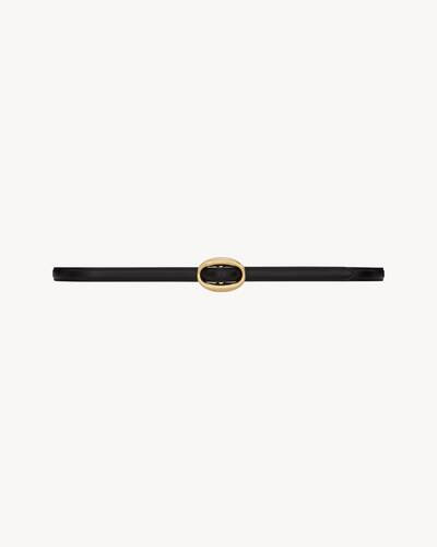thin belt with an oval buckle engraved with the SAINT LAURENT PARIS signature. | Saint Laurent Inc. (Global)