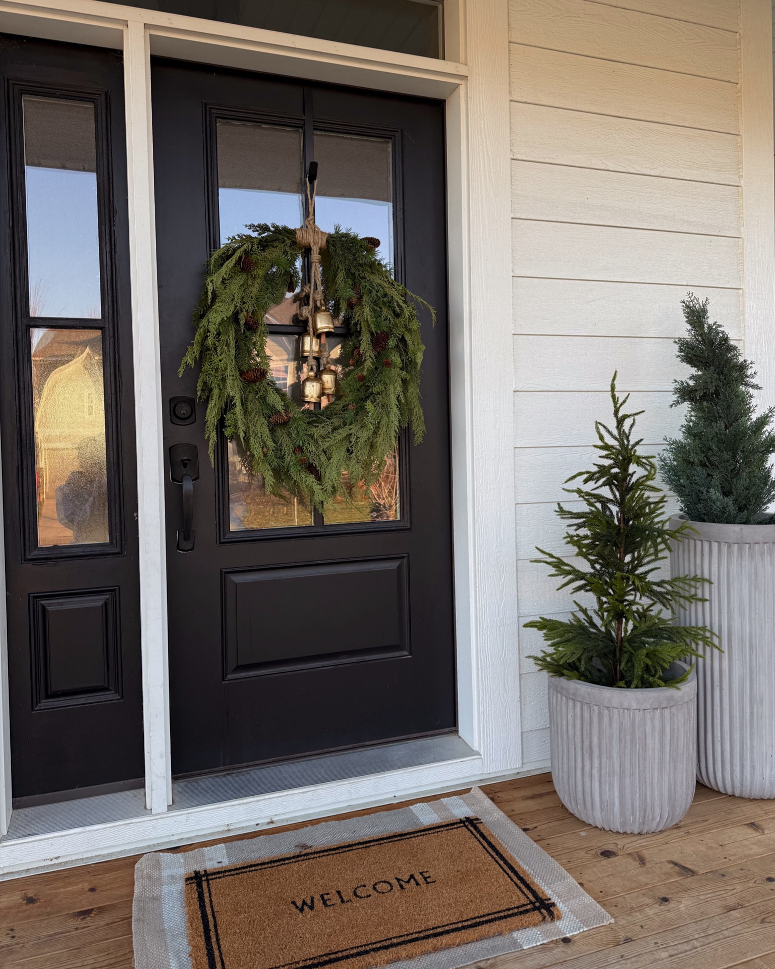 Winter front porch decor 🌲✨🔔 
 
I added the bells from Amazon wreath to level it up! It would also look beautiful with a big velvet ribbon 🎀 Wreath is a splurge, but gorgeous and realistic. On sale for 30% off right now for Black Friday!! 

Planters are medium and extra tall 

#LTKSaleAlert #LTKCyberWeek #LTKHome