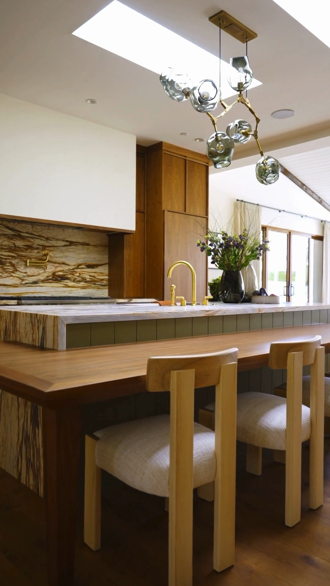 A warm, light-filled Arizona mid-century modern kitchen that feels both sculptural and livable.

The waterfall island in Sherwin Williams Messenger Bag, paired with a custom walnut table and skylights above, gives the space a grounded, organic quality. The Calacatta Vintage marble backsplash adds natural texture that feels timeless and sophisticated.

Full home tour + sources:
https://www.homebunch.com/arizona-mid-century-modern-home-renovation-tour/

Interior Designer: @homesmithdesign | Video: Portal Media

Follow my LTK shop for more thoughtfully designed house tours and home inspiration — never the same, never boring. ✨

#MidCenturyModern #KitchenDesign #ArizonaHomes #WarmInteriors #HomeRenovation #HouseTour

#LTKOver40 #LTKSaleAlert #LTKHome