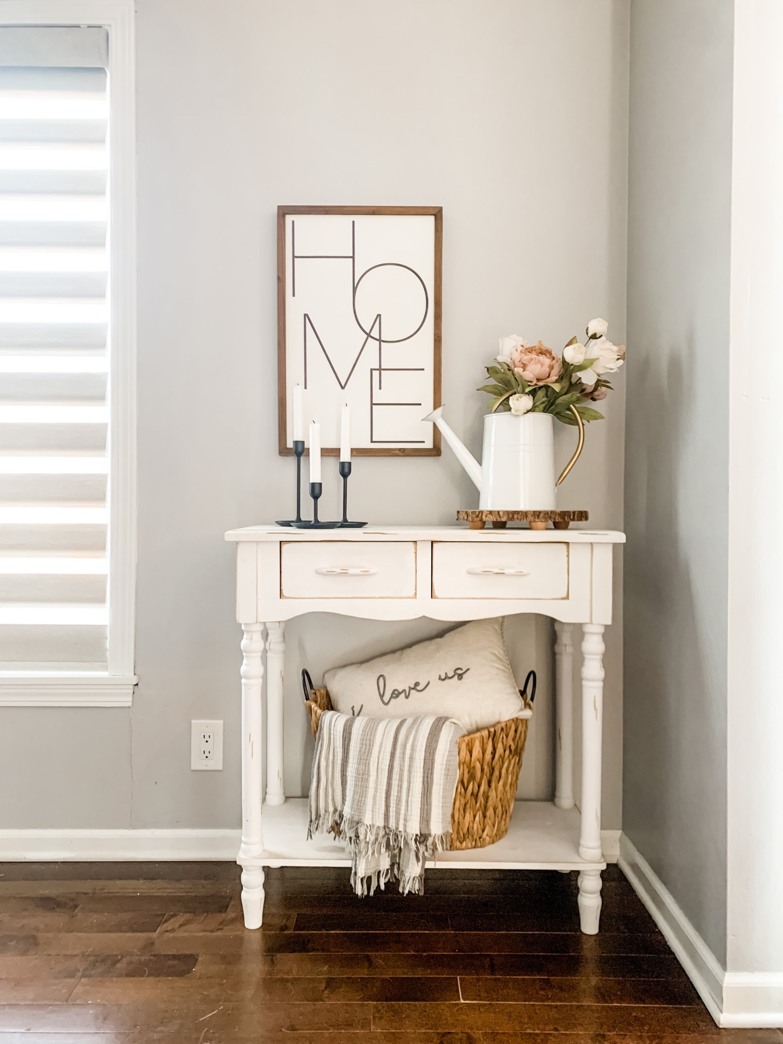 Styling an entryway table…

Start with a piece of art, or a mirror, hung on the wall
Add candlesticks
A floral piece that fits your style
I love woven baskets for texture and function—a blanket and pillow are a perfect combo 