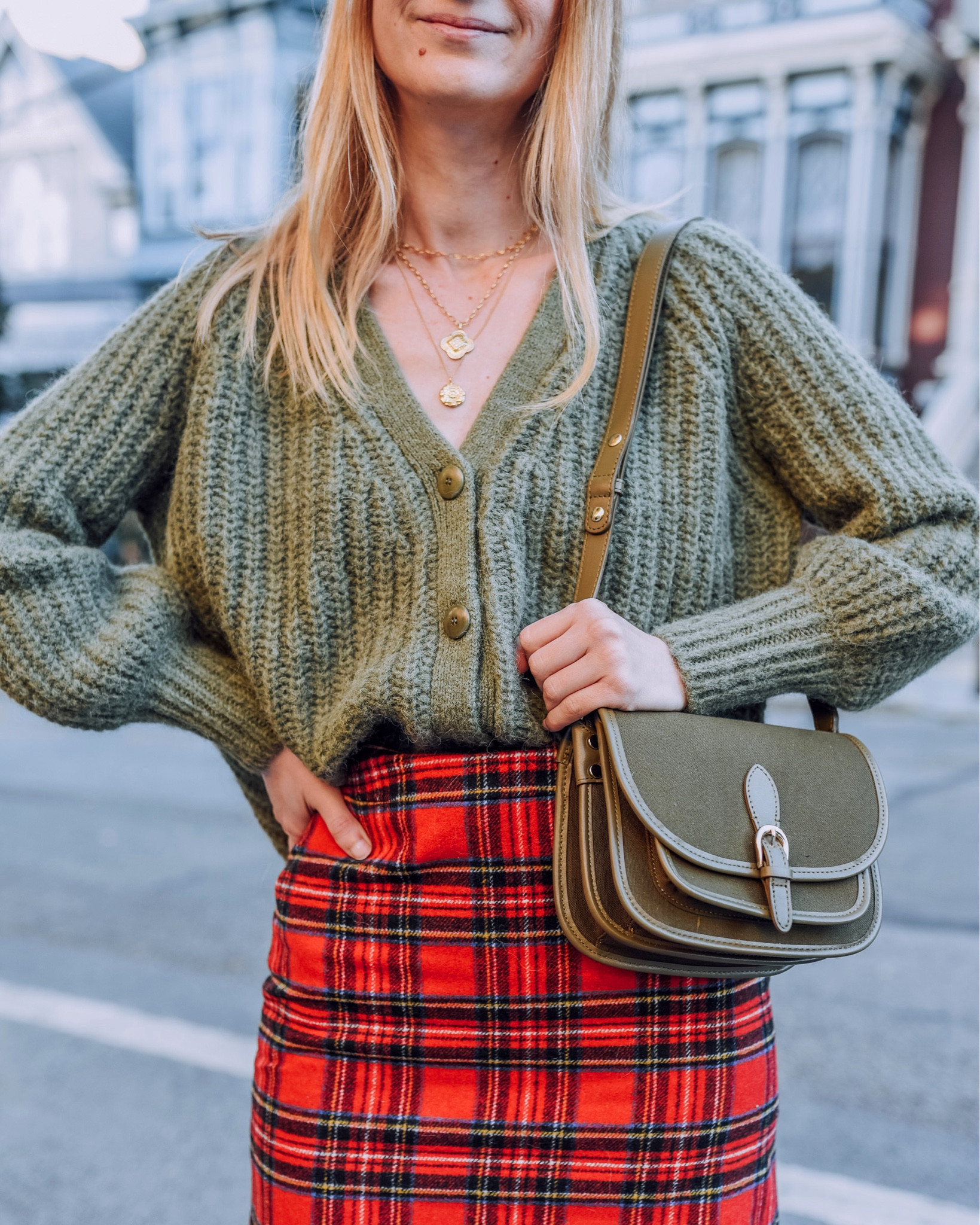 Holiday perfect outfit: short plaid mini skirt paired with khaki v neck cardigan and a khaki bag